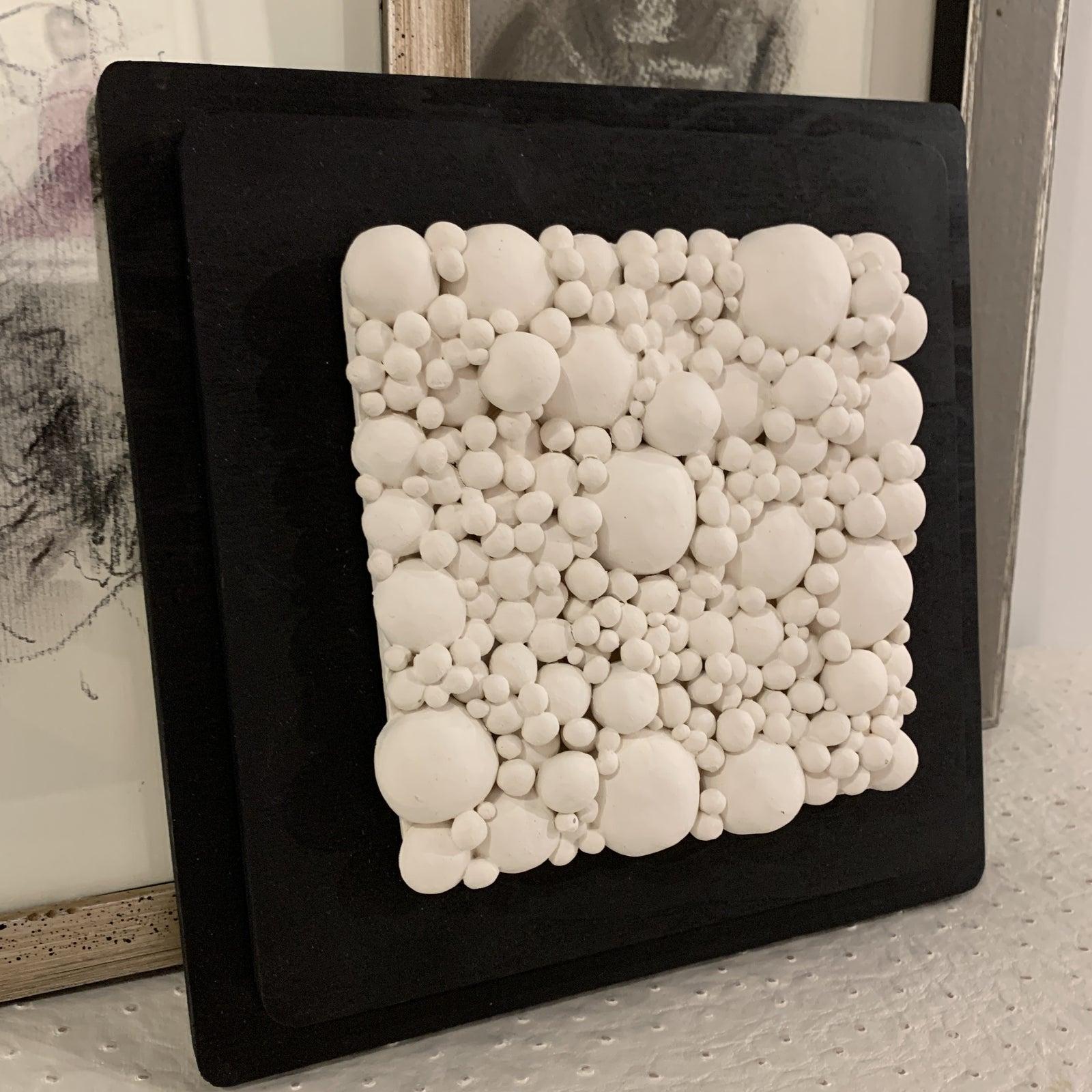 Stunning handmade pottery on custom wooden wall plaque. This ceramic design can be hung on a wall or layed on a table for display.
The gallery has a very small collection in black and white in this vein. Each piece is sold individually and had its