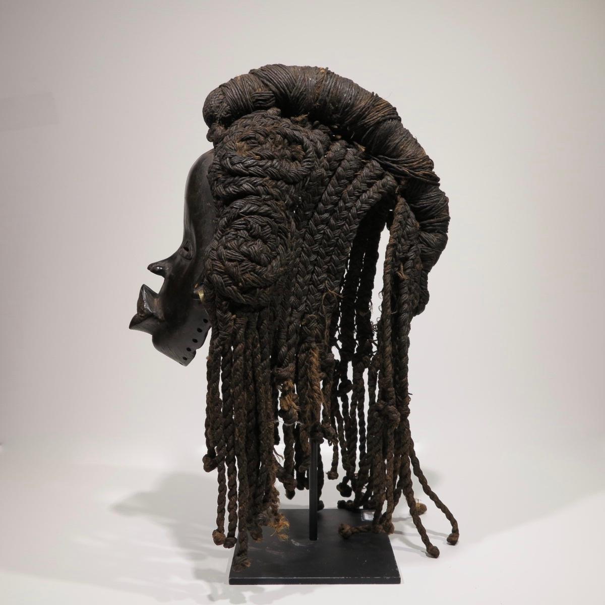 Beautiful 20th-century Dan Mask. Carved wood,  Liberia. Face measures 8.25 x 7 x 3.75 inches. Complete with attached rope and beeswax wig, measures 14 x 9 x 12.5 inches. Measures 18 inches tall with custom stand. 