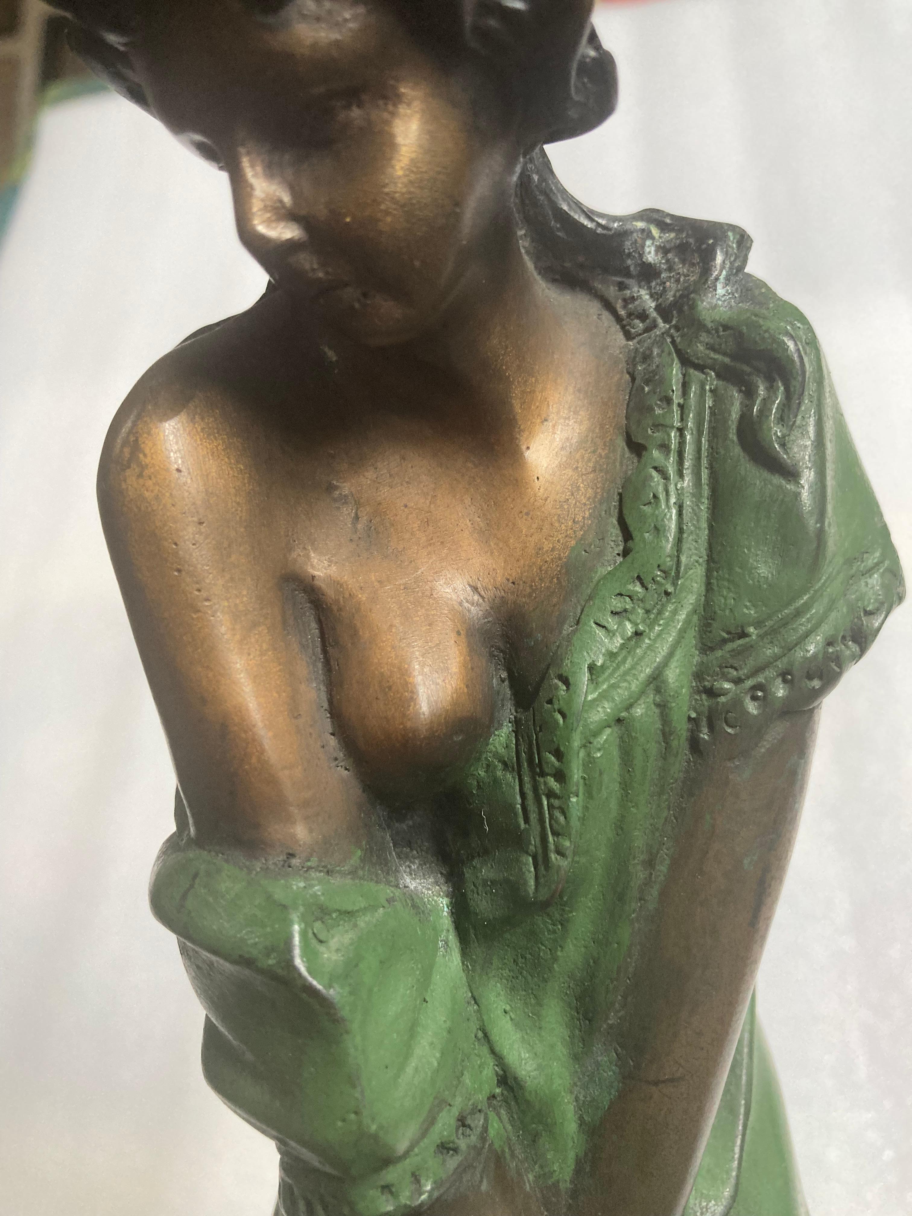 A gorgeous solid bronze on marble pedestal depicting a demure young woman observing something that appears to be just in front of her. Is she a bit timid, perhaps? A lovely patina has been adding to her clothing for contrast.  
