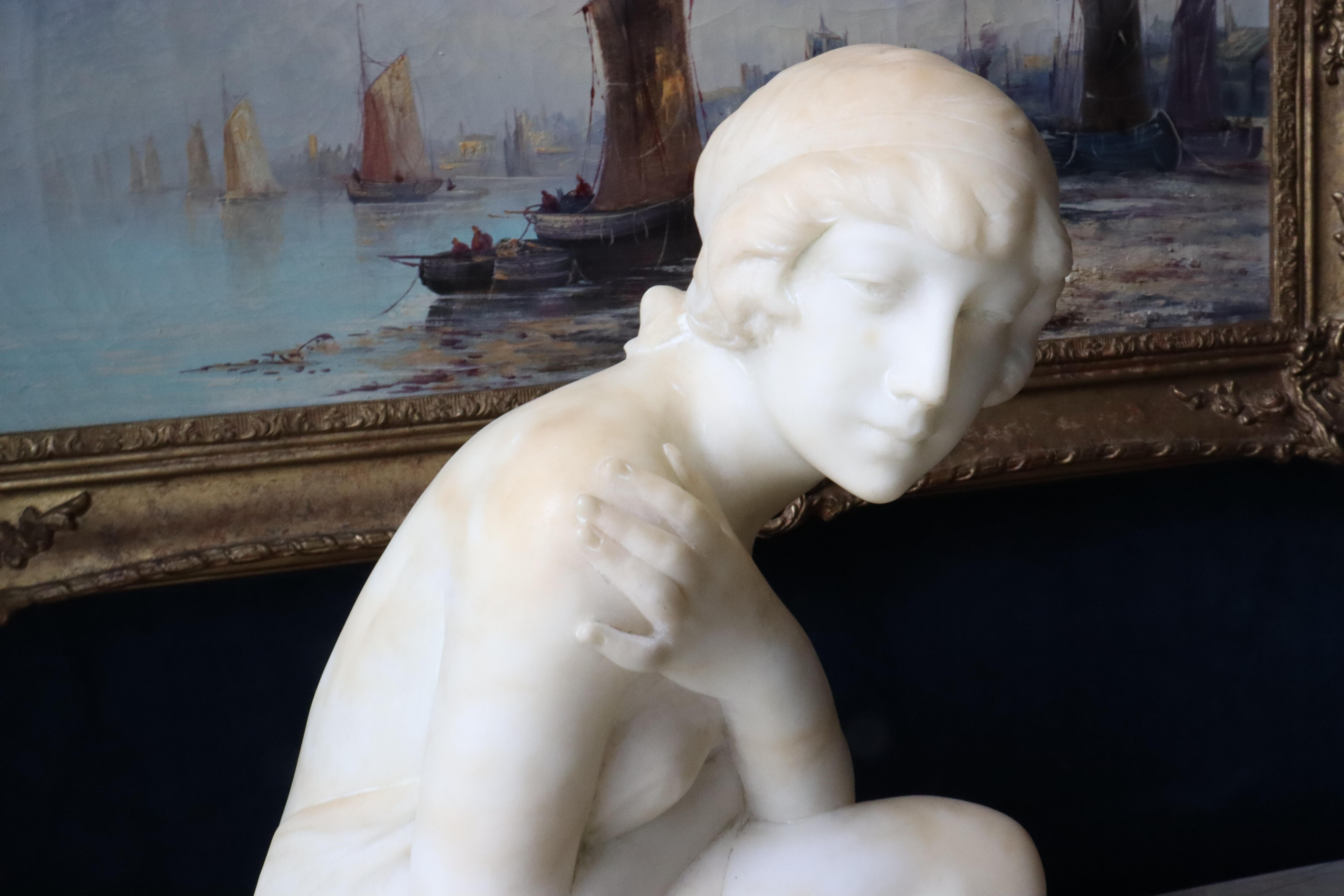 Sculpture en albâtre Art Nouveau italien du début du XXe siècle représentant une jeune baigneuse.  Le baigneur est assis sur une pierre, les bras croisés, dans une pose modeste.  Le baigneur est semi-nu.  Quelques éraflures et rayures mineures.  La