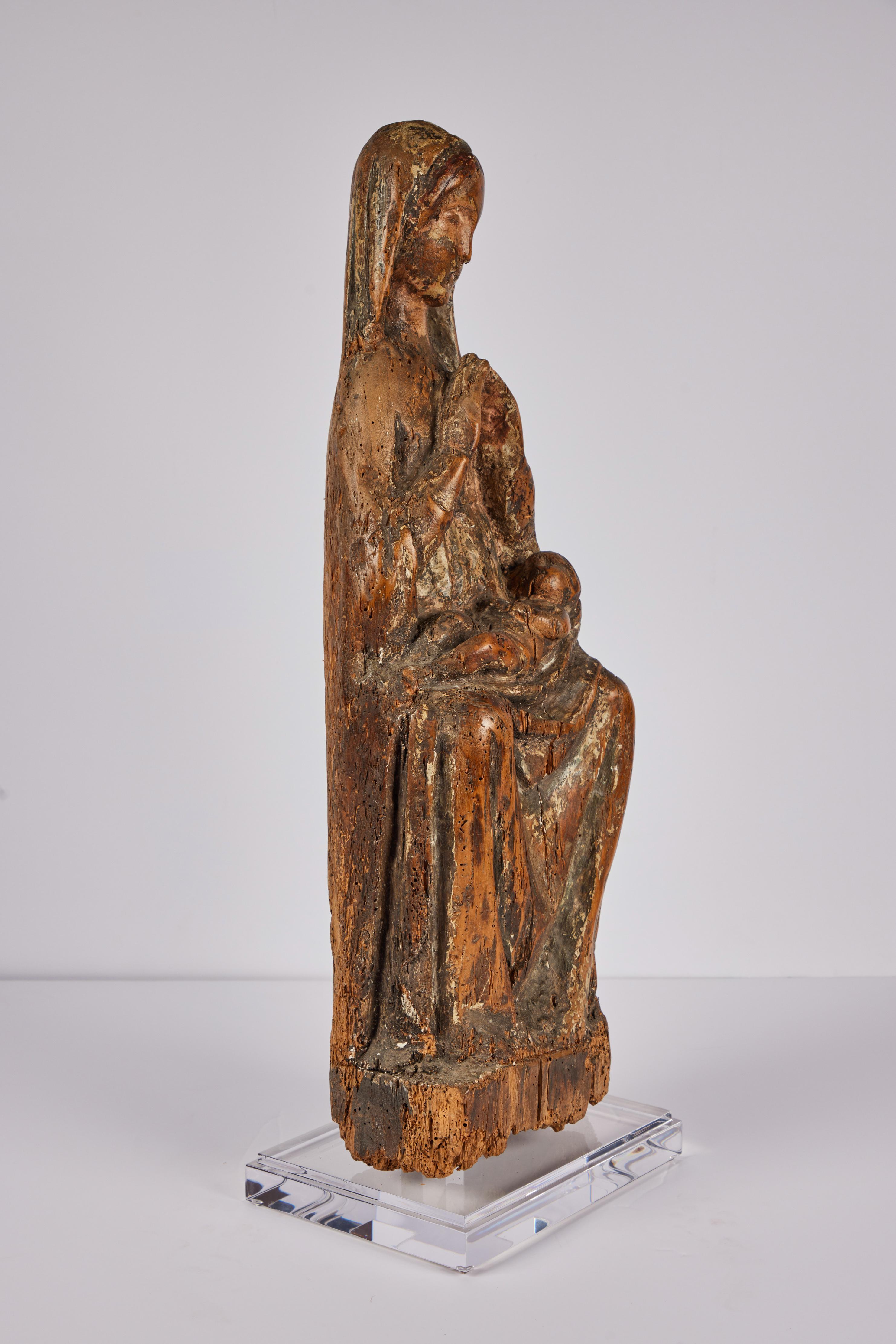 Eine stimmungsvolle, aus Holz geschnitzte Statue aus dem 14. Jahrhundert, die eine sitzende Maria mit dem Christuskind auf dem Schoß darstellt. Das Stück hat eine schöne Patina mit polychromen Farbspuren. Jetzt auf einem modernen, abgestuften