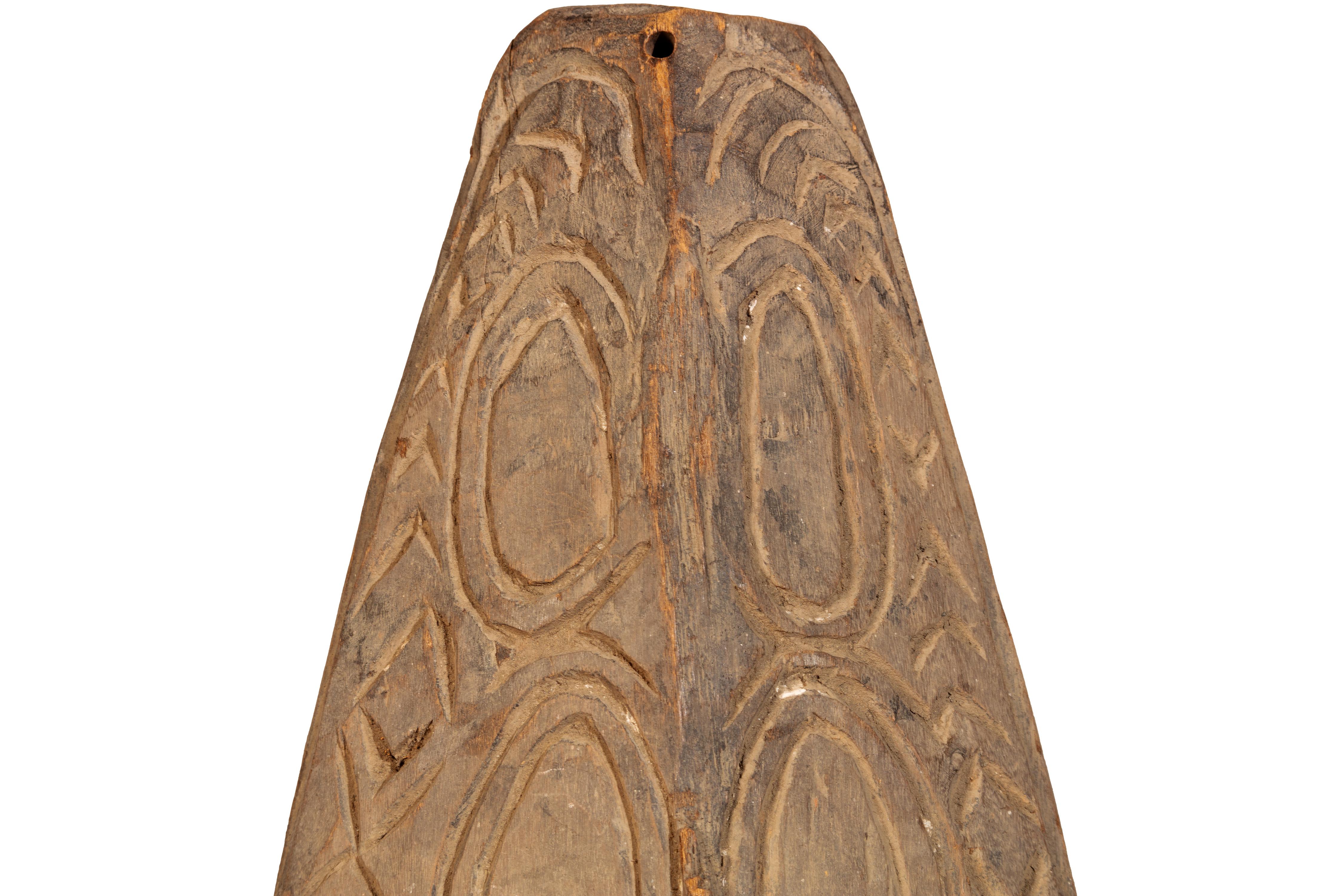 This mask was created by an unknown artist from New Guinea. It depicts an elongated face with carved wood and cowry shells for eyes.

Mask: 29 x 8 in, includes a metal stand. 