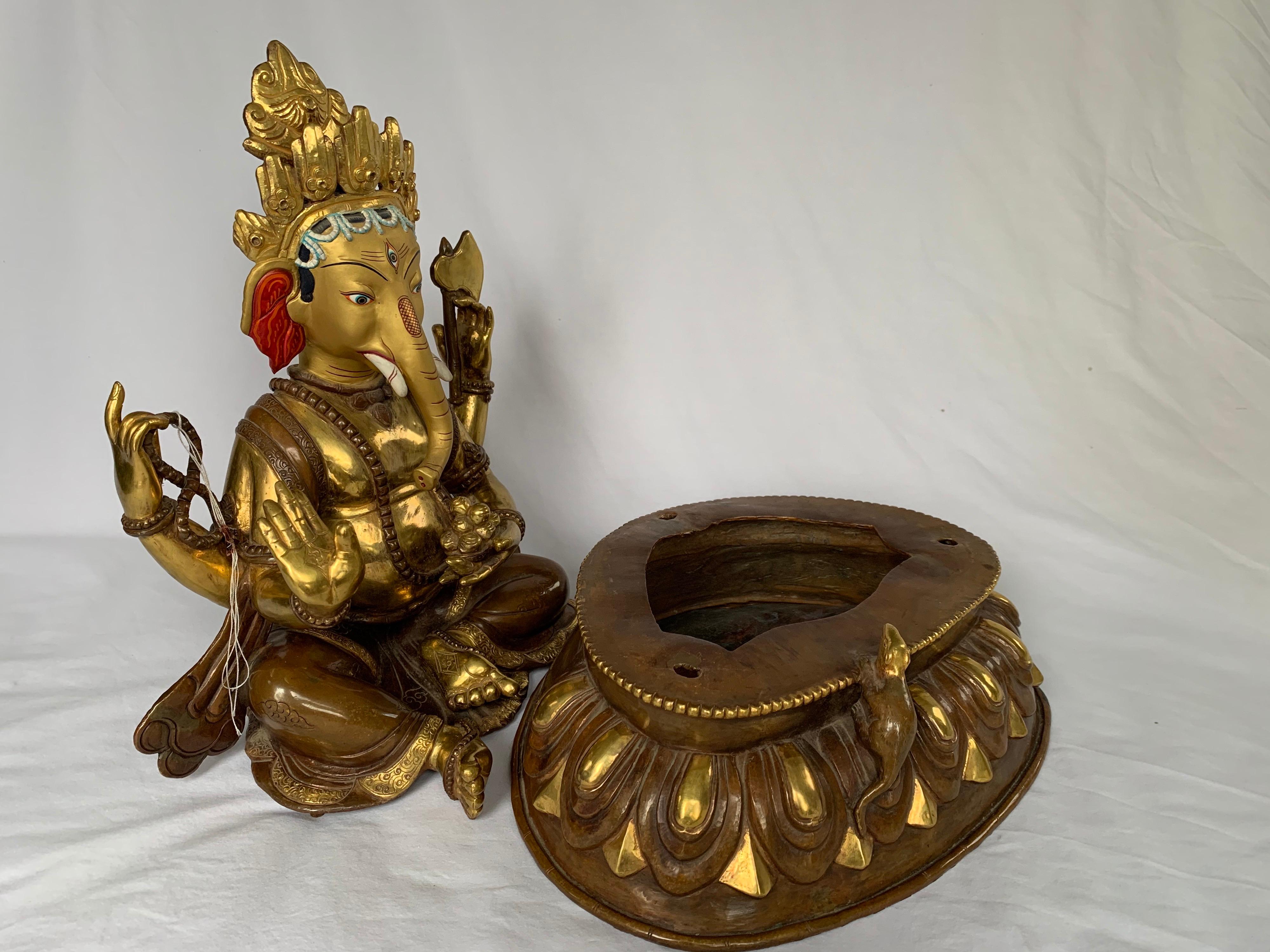 This statue is handcrafted by lost wax process which is one of the ancient process of metal craft. Ganesha is seated on lotus with one leg folded and another slightly extended outward. One hand is holding an axe and another a rosary, third hand is