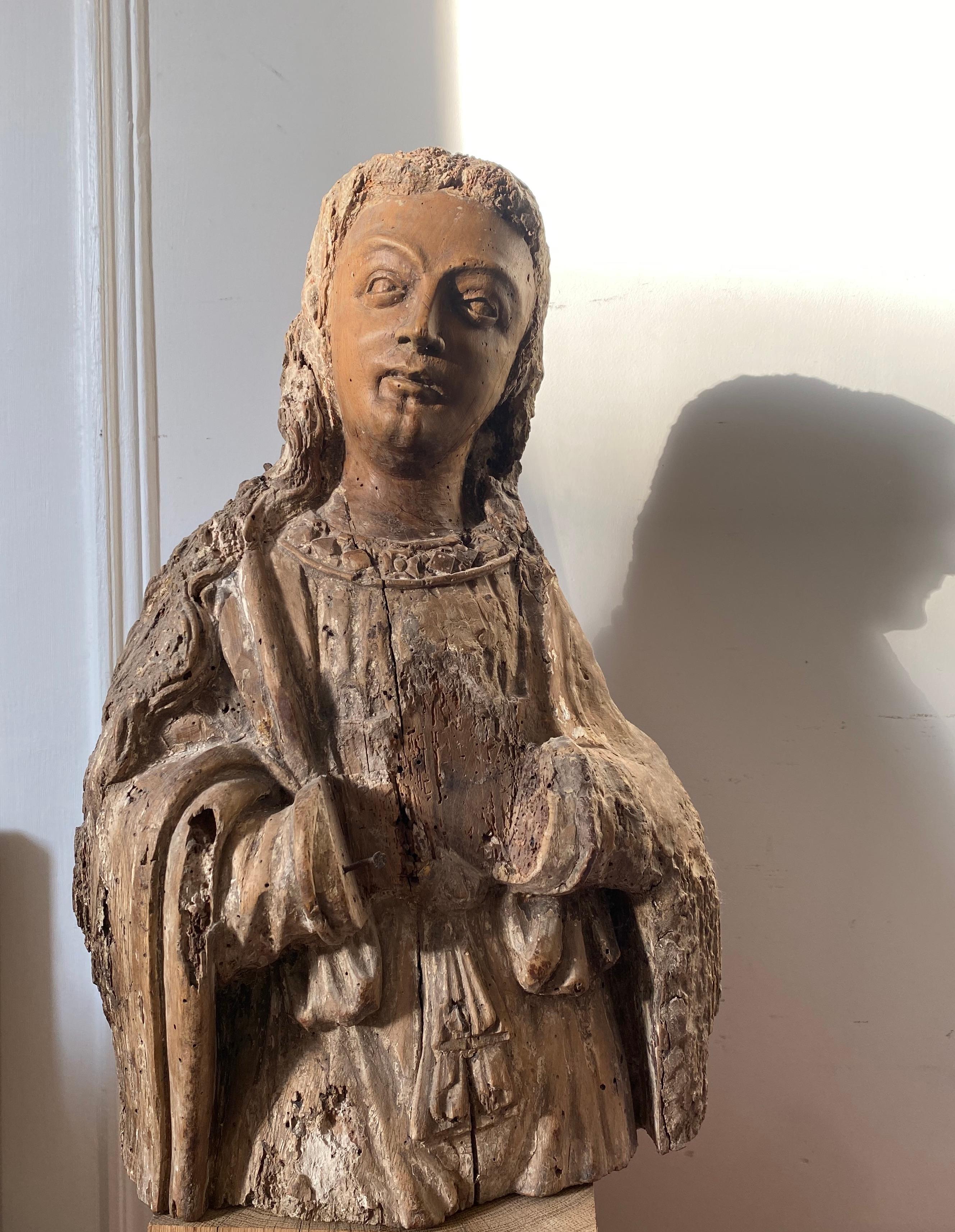 Este joven santo o ángel ha sufrido a lo largo de los siglos, pero su espíritu no se ha quebrantado y, milagrosamente, su bello rostro ha permanecido intacto. De rostro amable y casi sonriente, su presencia es benévola y etérea. 
Fechado hacia 1500