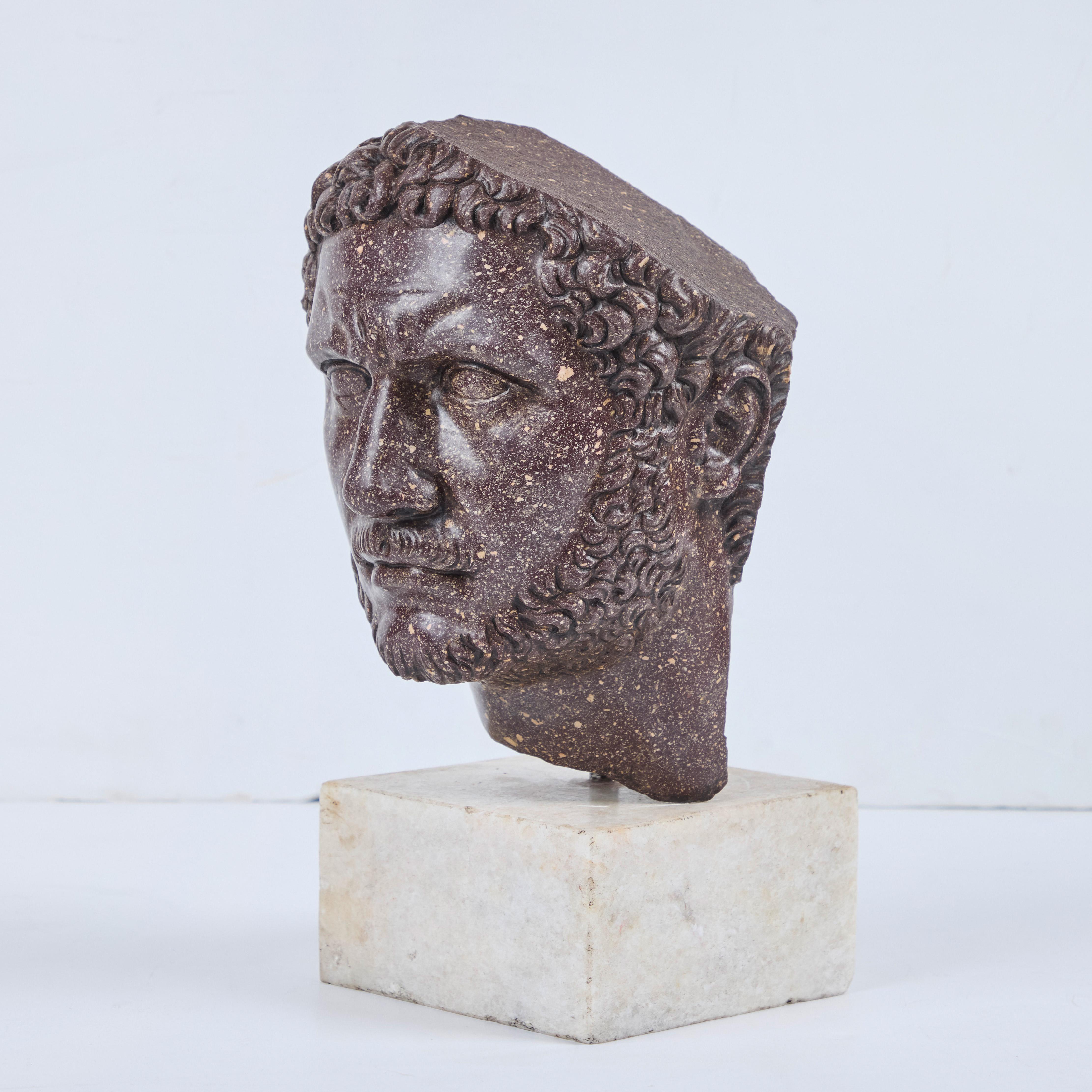 An 18th century, hand carved porphyry head of “Marcus Aurelius” mounted on a Carrara marble base.  

