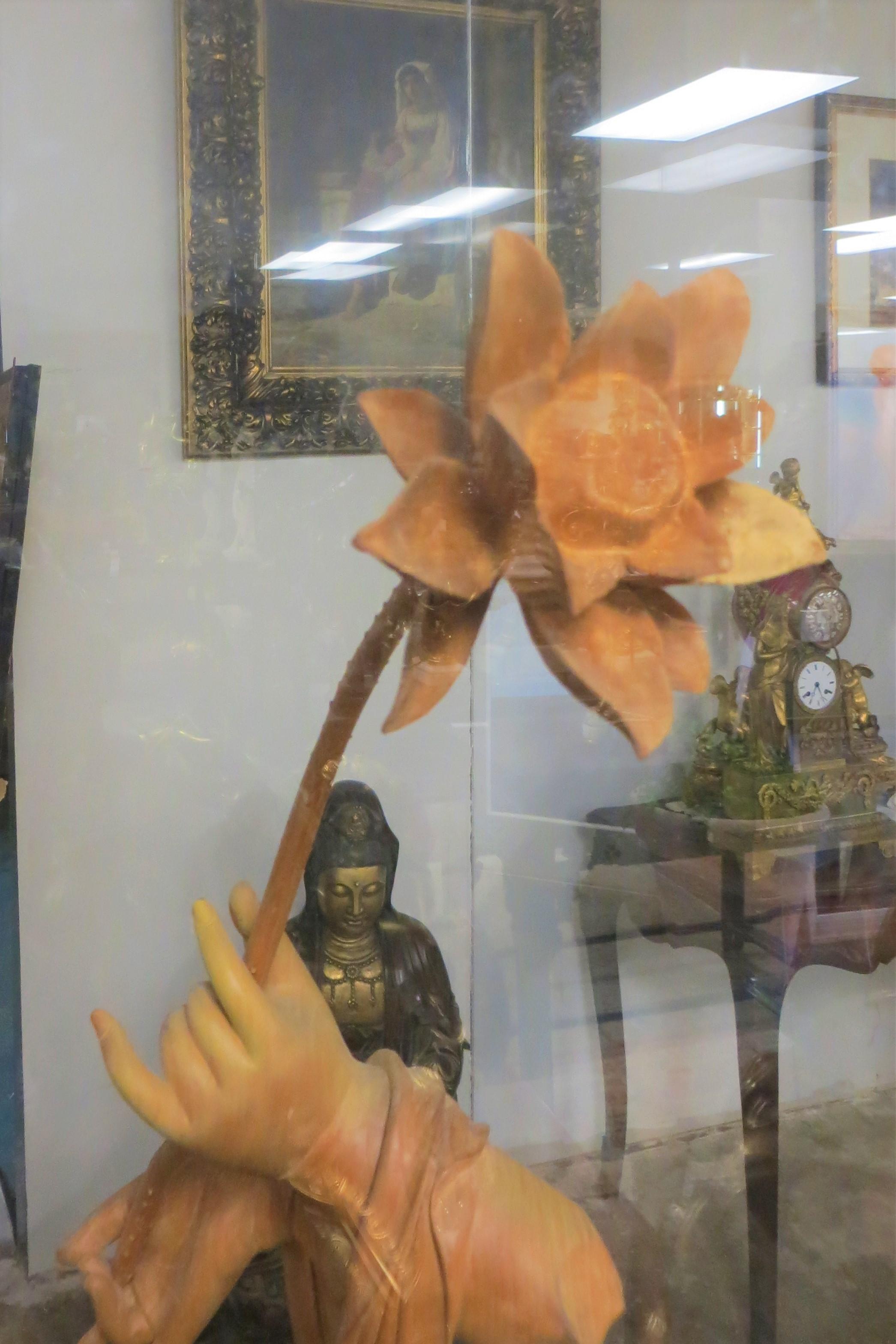 Wooden sculpture of a Chinese artist named Bones representing the hand of Boudha holding a lotus flower.
put in a plexiglass box .