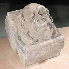 Gargoyle dal volto umano/grottesco, uomo sorridente e sciocco; scultura gotica in pietra calcarea