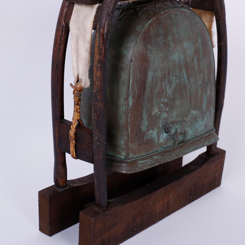 Elephant bell and clapper that rings with a deep rich tone and cast in bronze. Having acquired a verdigris patina and presented on a rustic wood and hide swing.