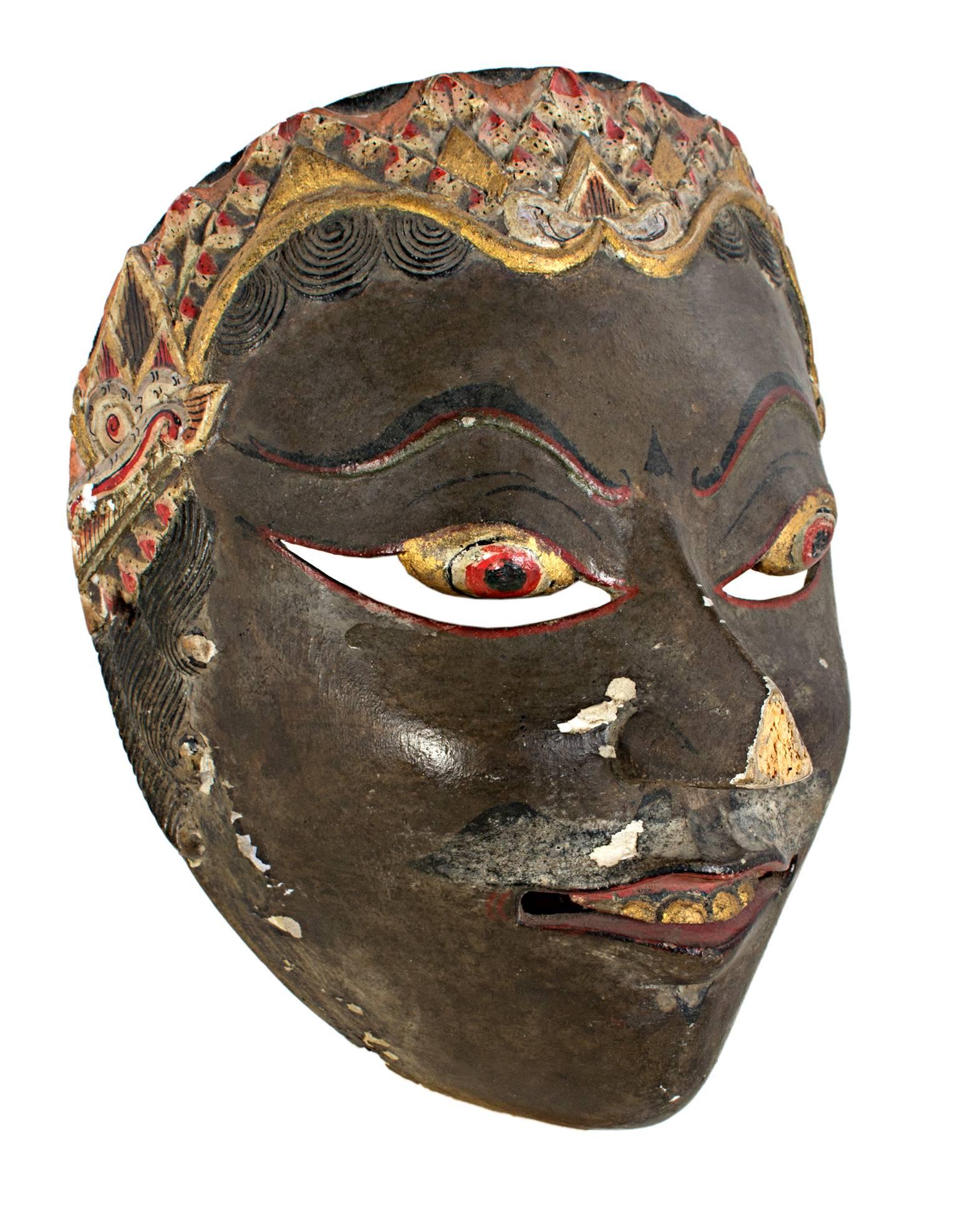 Diese Maske, die von einem unbekannten indonesischen Künstler geschaffen wurde, zeigt dunkle Sünden, goldene und rote Augen, Zähne und Haare. Es ist ungefähr 7