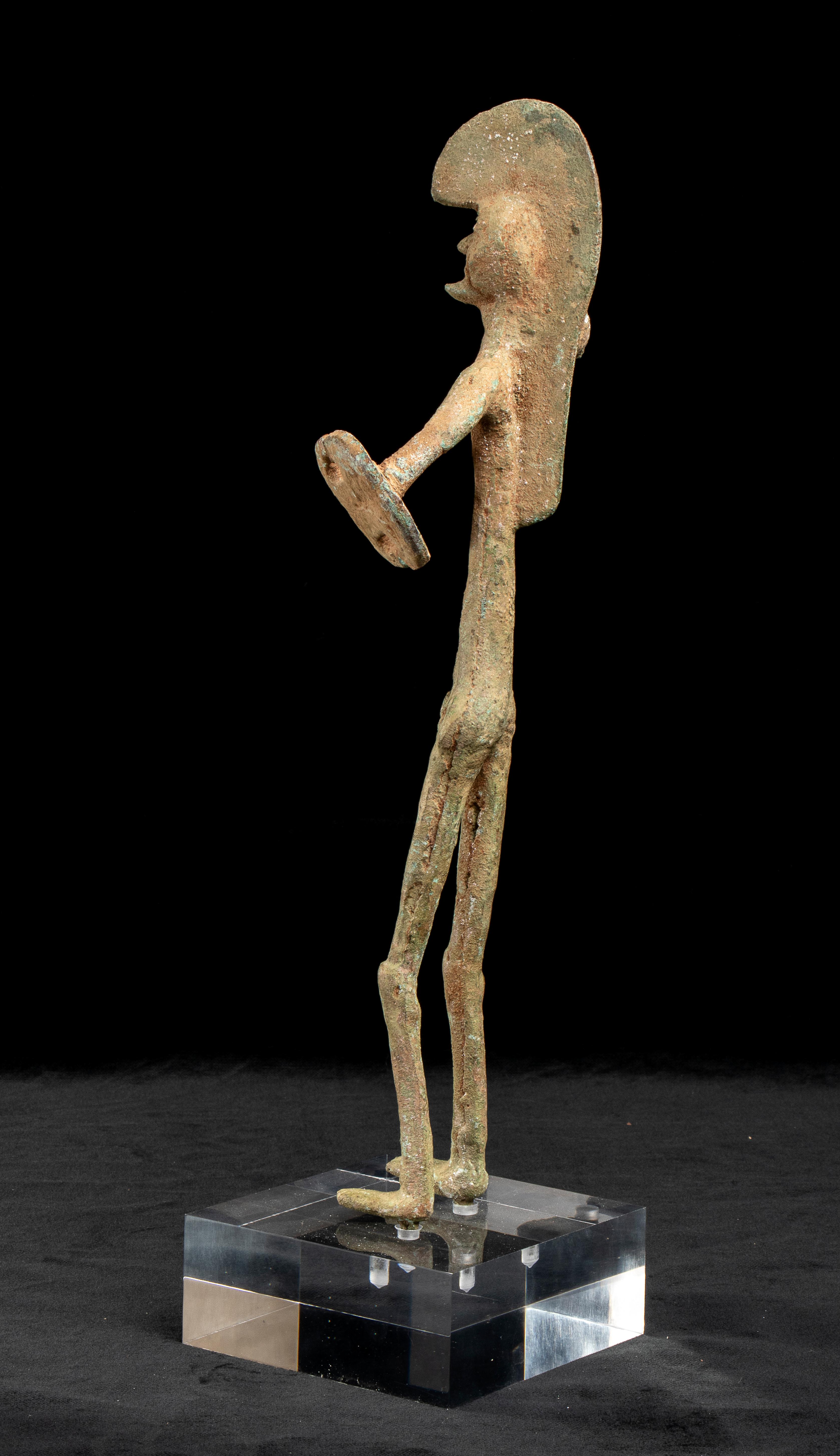 A gran tour bronze sculpture of an Etruscan Warrior standing on a plexiglass base. The Warrior strides forward, brandishing a bent spear held in his right hand. His left arm is lowered and held beside his thigh and  held a shield in his left hand.