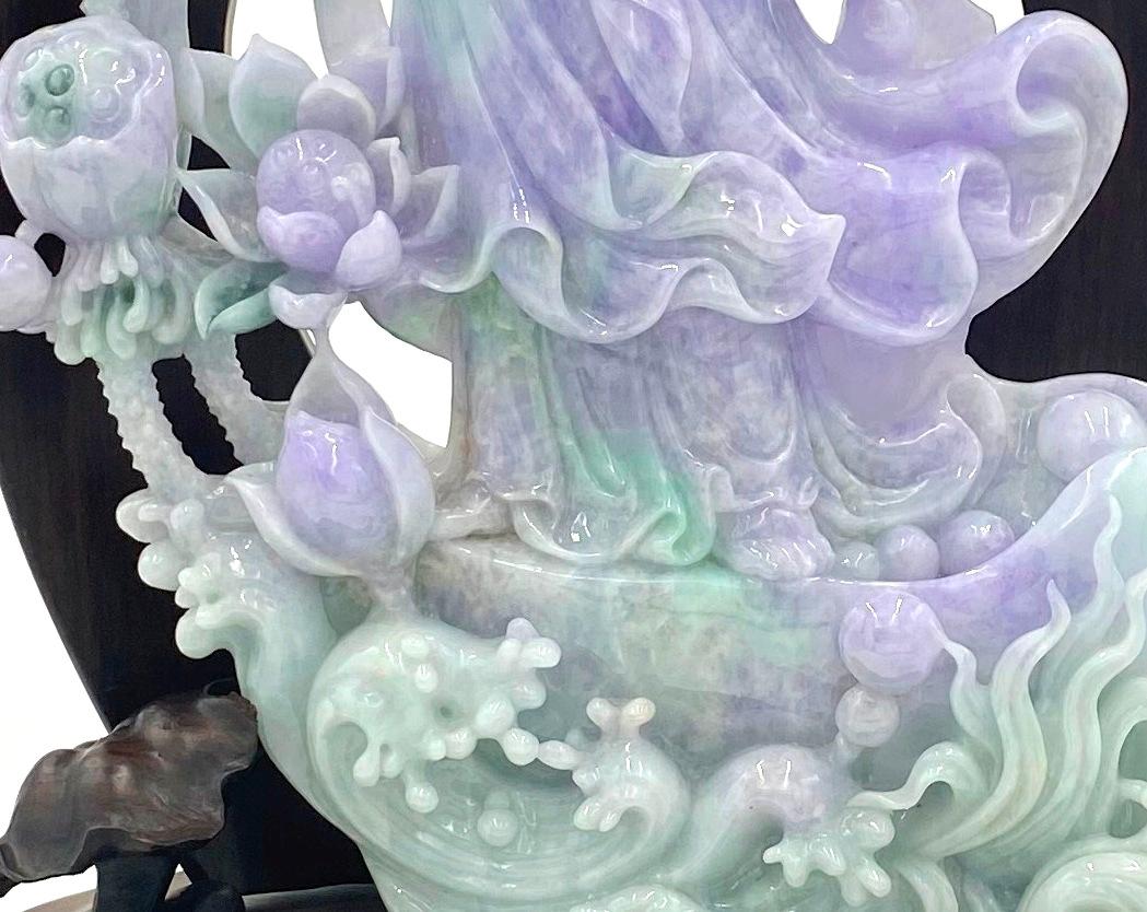JD1318 
Jadeite Jade Quan Yin carving with a unique color combination of translucent Green, Lavander and white hues. 

This intricately hand carved Guan Yin has a full face with arched eyebrows and downcast eyes casting a serene aura. She wears a
