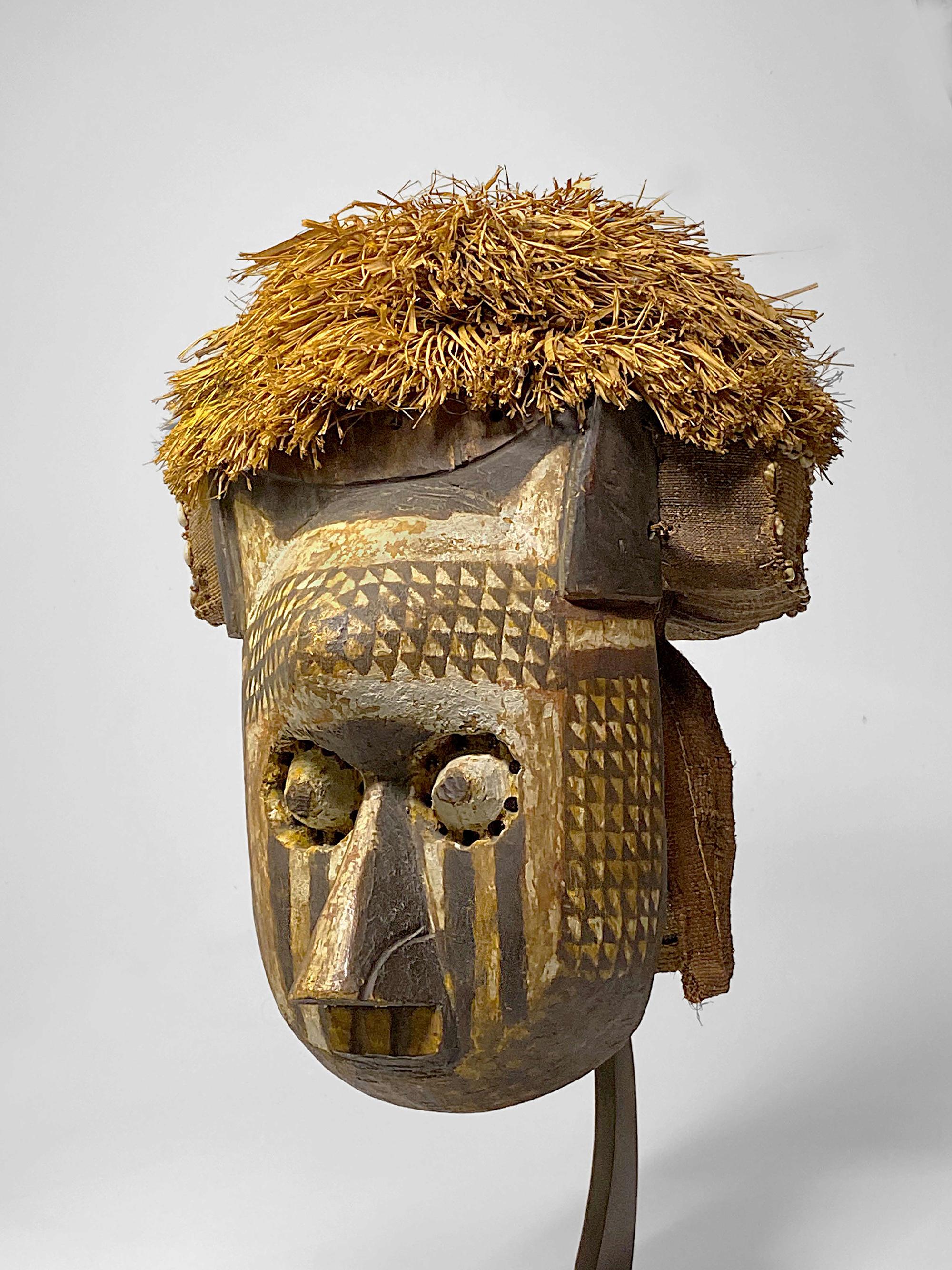 This classic early 20th century Itok mask is from the Kuba/Ngeende culture in the Democratic Republic of the Congo.  It is rare to find an example with original raffia attachments.  This is a particularly graphic example painted with white and black