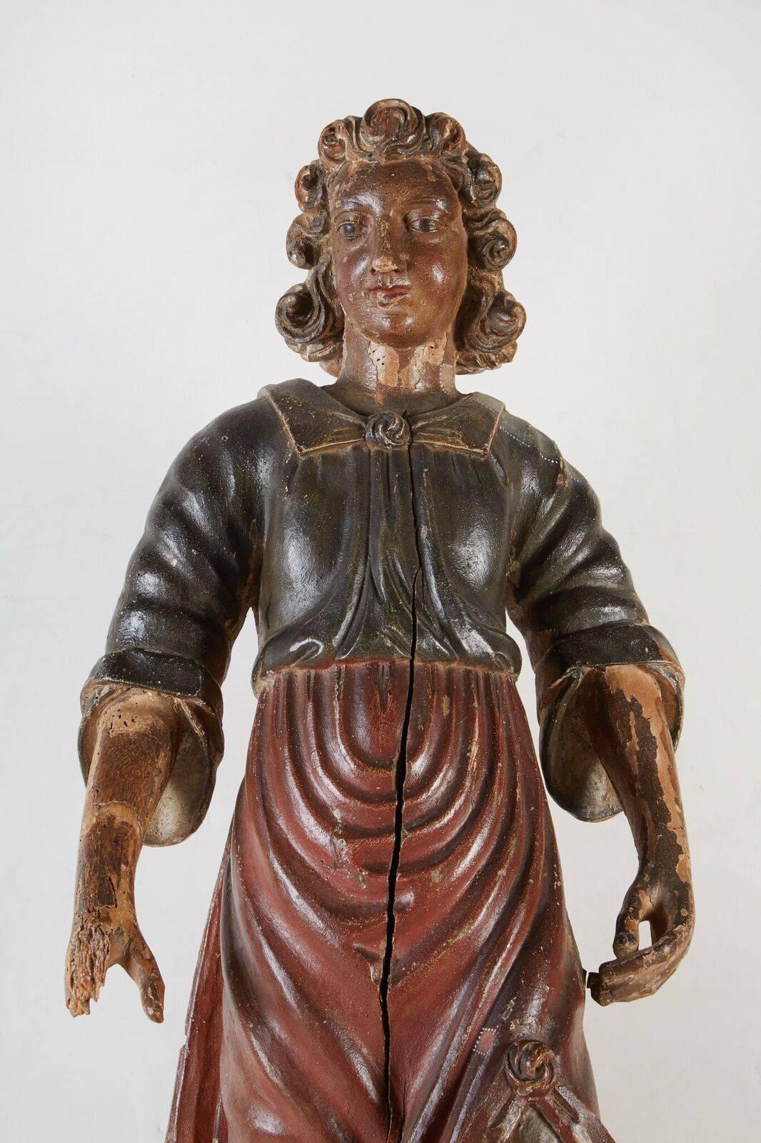 Hand-carved and painted, polychrome, Roman Santos figure in mid-stride. The figure wears stylized, flowing robes and stands atop a period base.
