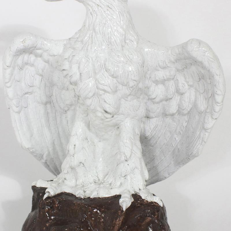 Opposing pair of lifesize Majolica or glazed terra cotta eagles. Executed with fine detail right down to the talons. Perched on mountainous bases these birds bring a formidable attitude that are symbols of trust, bravery and strength. These will sit