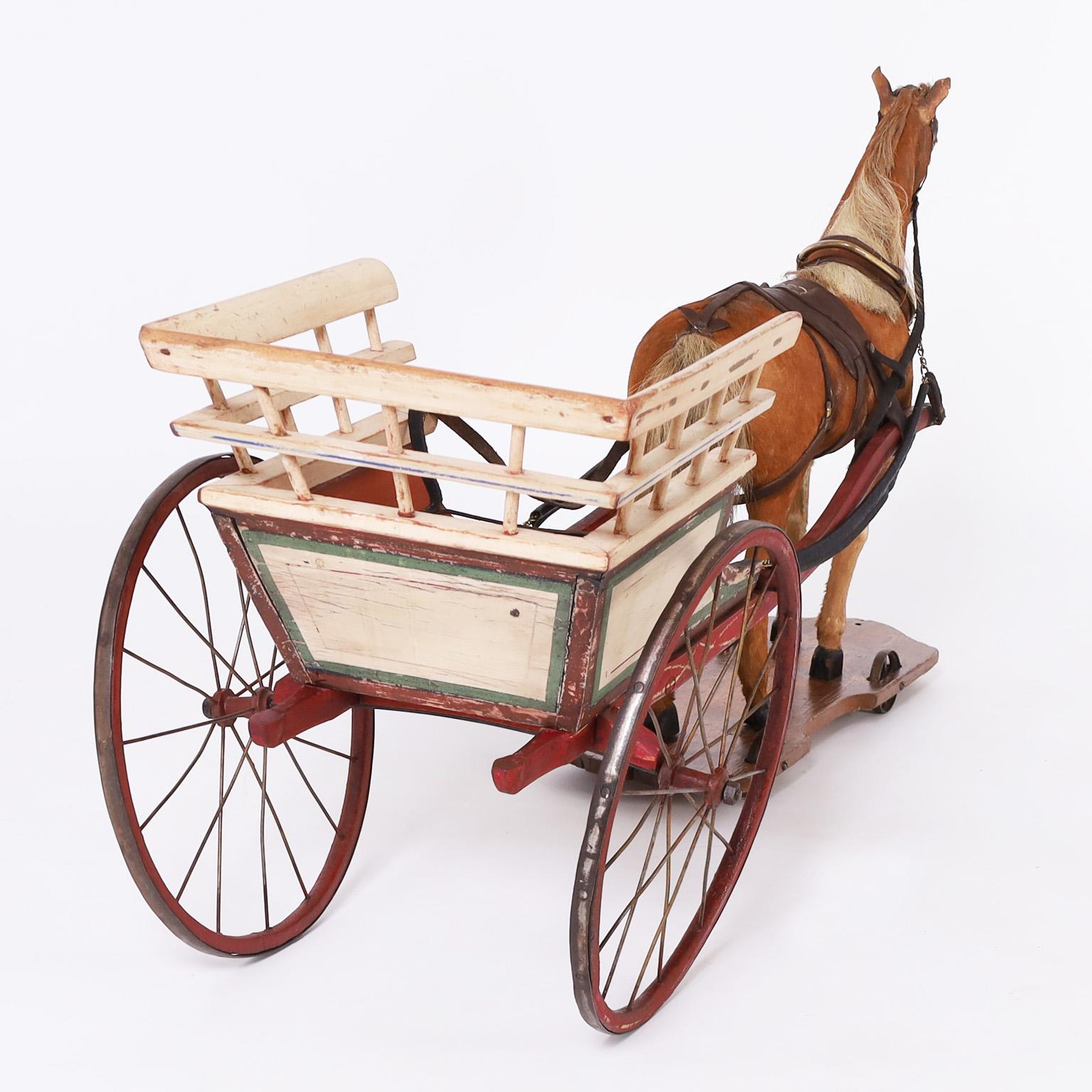 Impressionnant jouet cheval et charrette fabriqué à la main avec un cheval réaliste recouvert de peau de vache et équipé d'une sellerie authentique sur une plate-forme en bois avec des roues. Le chariot peint à la main a des roues en bois avec des