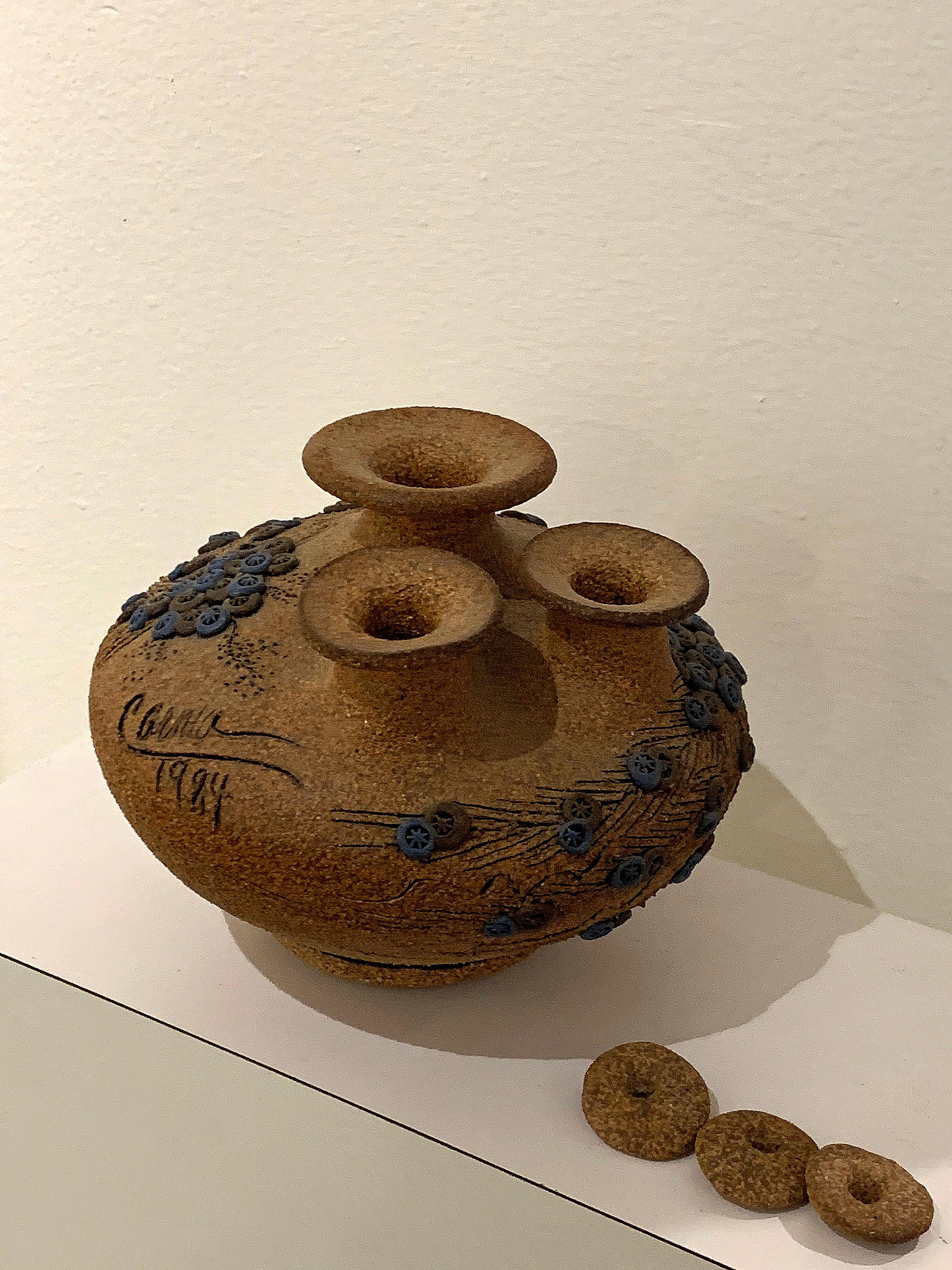 Beautifully lidded ceramic vase. Blue flowers complement the earthen brown.