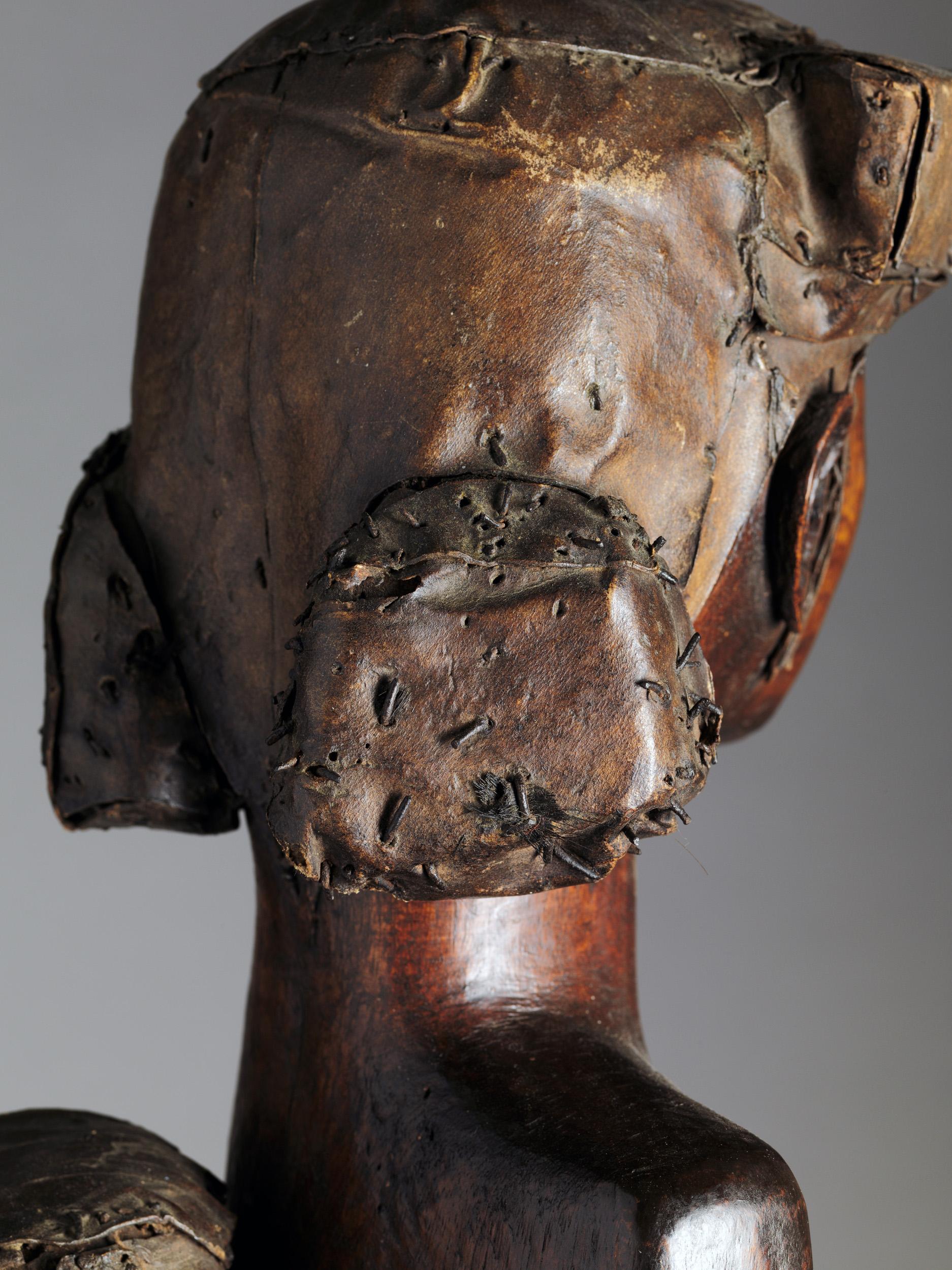 Standing Fang Mabea Maternity of Museum quality, holding a pestle with both her hands. The mother's head is slightly turned to the left, while the child, which she carries on her back, has his head turned to the right. Her left leg indicates a