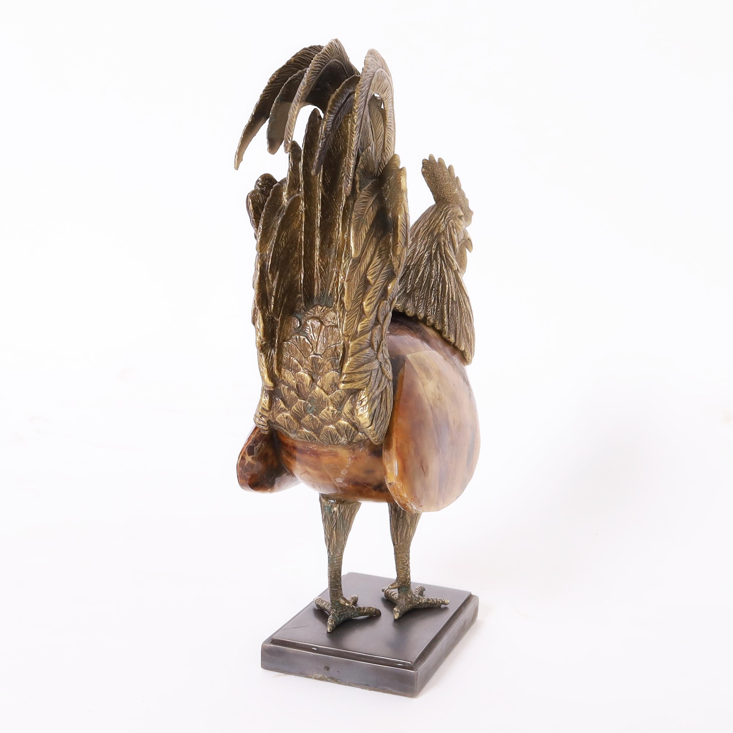 Destacada escultura o figura de gallo con actitud chulesca realizada en bronce y penshell y presentada sobre una base de metal. Firmado Maitland Smith en la parte inferior. 