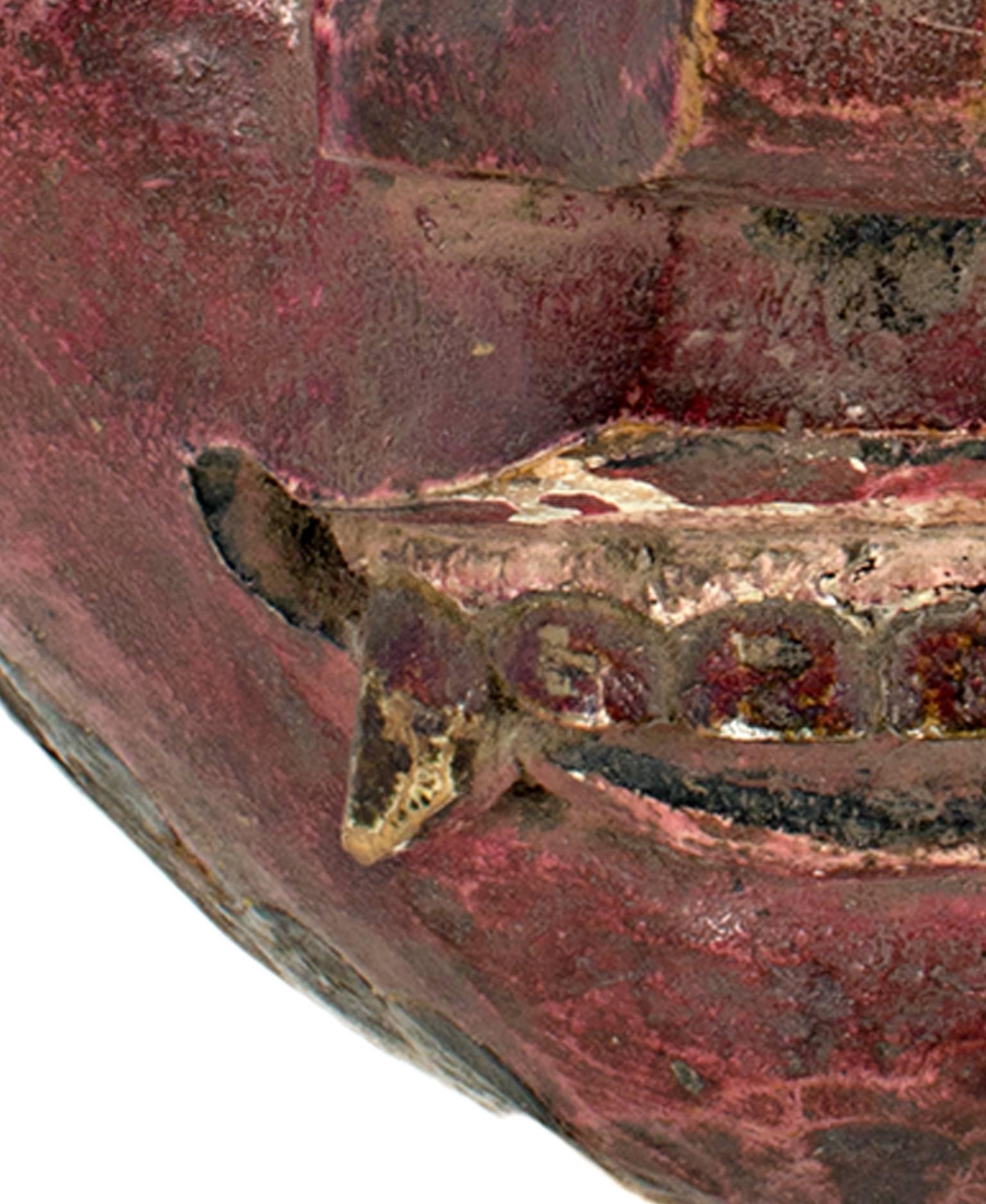 This mask, which features a face with round eyes, fangs, and a beet red face, was created by an unknown Indonesian artist. It is approximately 7 1/2