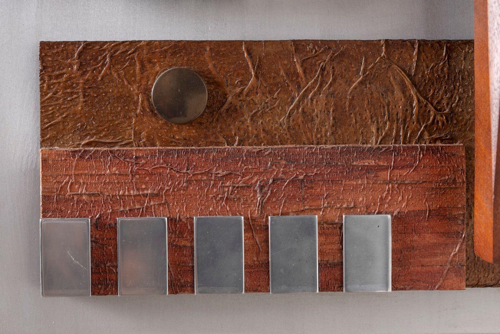 Questa scultura da parete originale dell'artista texano Stuart Mathews, audace e architettonica, esemplifica la cruda eleganza del design brutalista. Realizzata in metallo e legno strutturato con forme geometriche ben definite e una composizione a