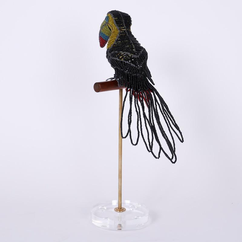 Divertente scultura di uccello realizzata con perline di vetro su una struttura di metallo e seduta su un trespolo di legno sostenuto da un'asta di ottone su una base di lucite.