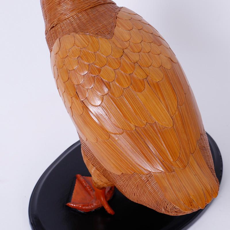 Wicker duck from with an intricate woven wicker structure and highlighted with wood wings and a sculpted bill and feet. Presented on a lacquered wood base.  