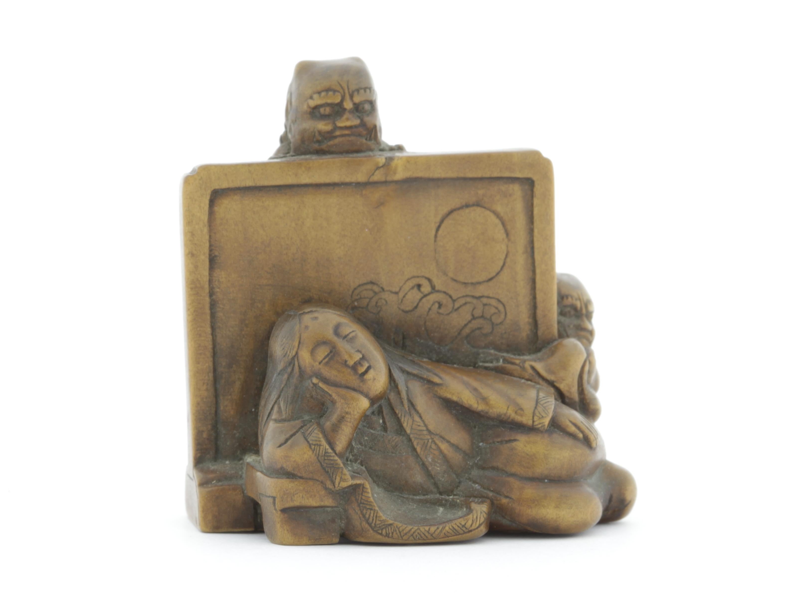 This netsuke is made entirely out of wood and depicts a sleeping lady being watched by two oni (demons). Her long hair is loose and her eyebrows are carved high above on her forehead, suggesting her noble background. The screen behind her shows a