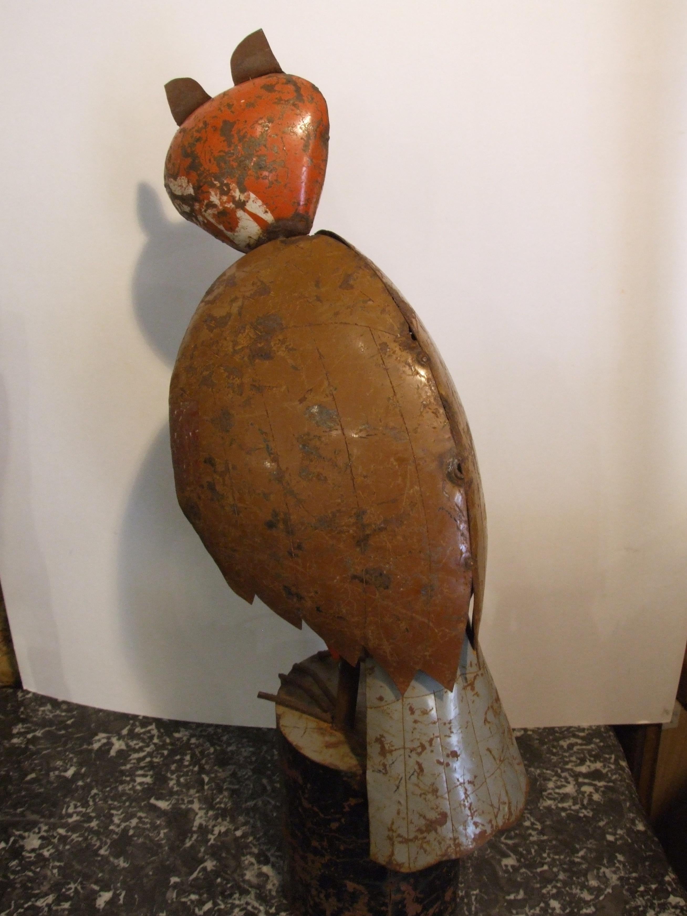 Sculpture depinctin an owl made by painted metal foil, standing on a similar base. a unique piece