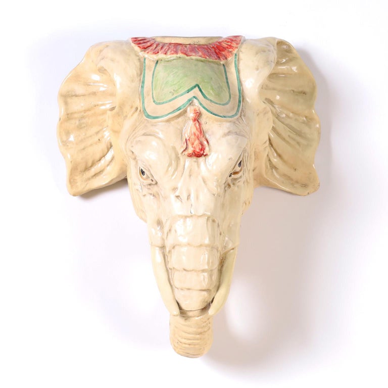 Elephant head wall sculpture crafted in composition and whimsically decorated with enamel.