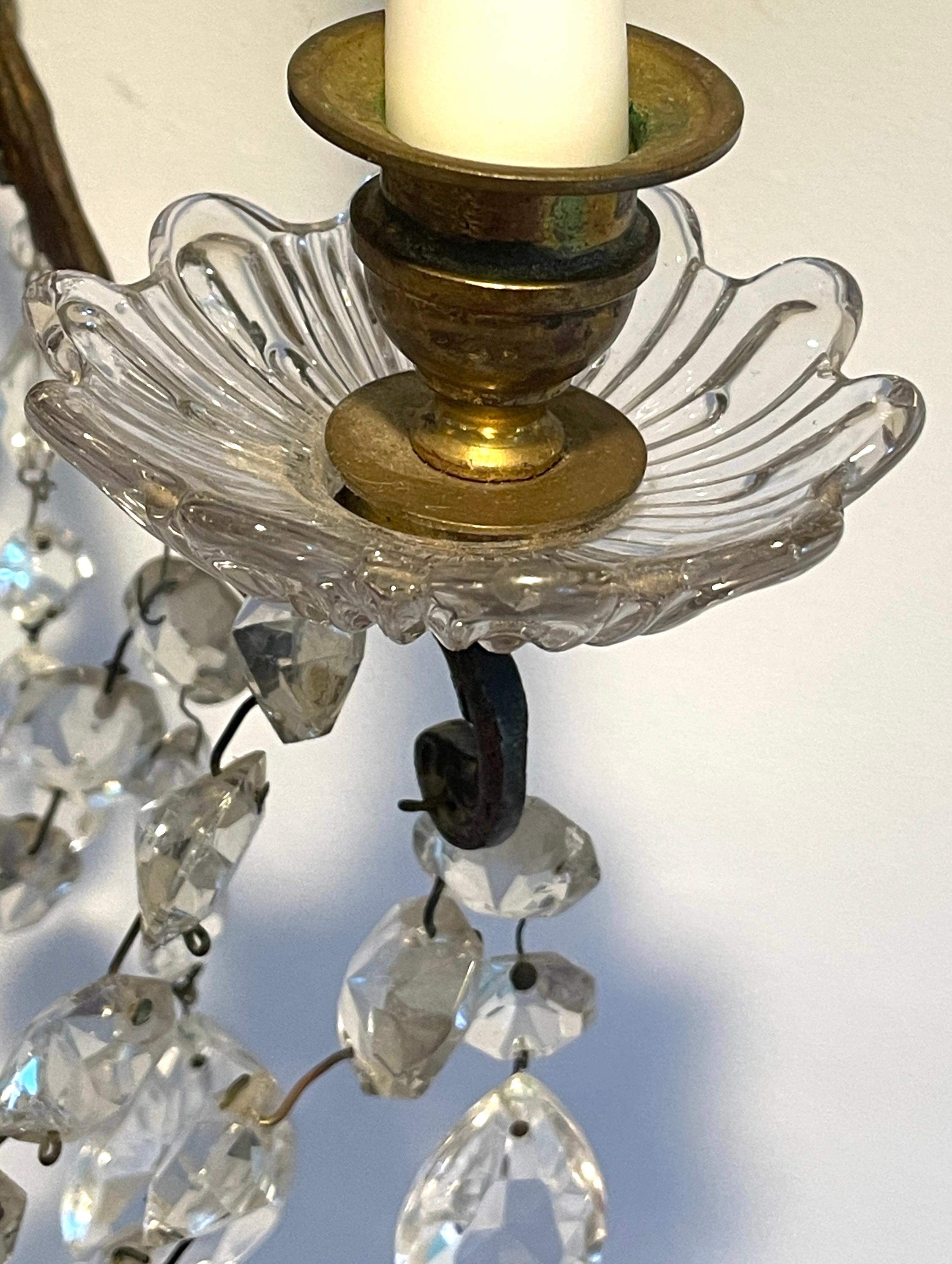 Questa coppia di appliques è composta da un candelabro verticale che sovrasta tre graziosi bracci fluenti, ciascuno dotato di tre candelabri che sovrastano bobeches sagomate e modellate. Ciascun braccio della candela è appeso con catene di cristalli