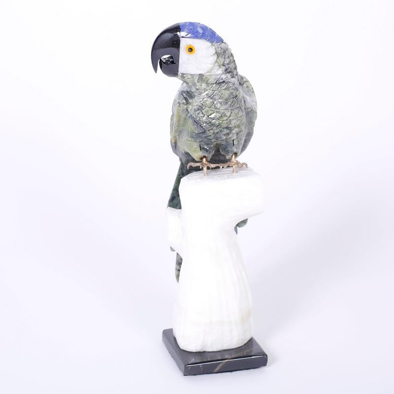 Pair of birds carved from various semiprecious stones with an amusing expression and brass feet perched on carved stone tree trunks.