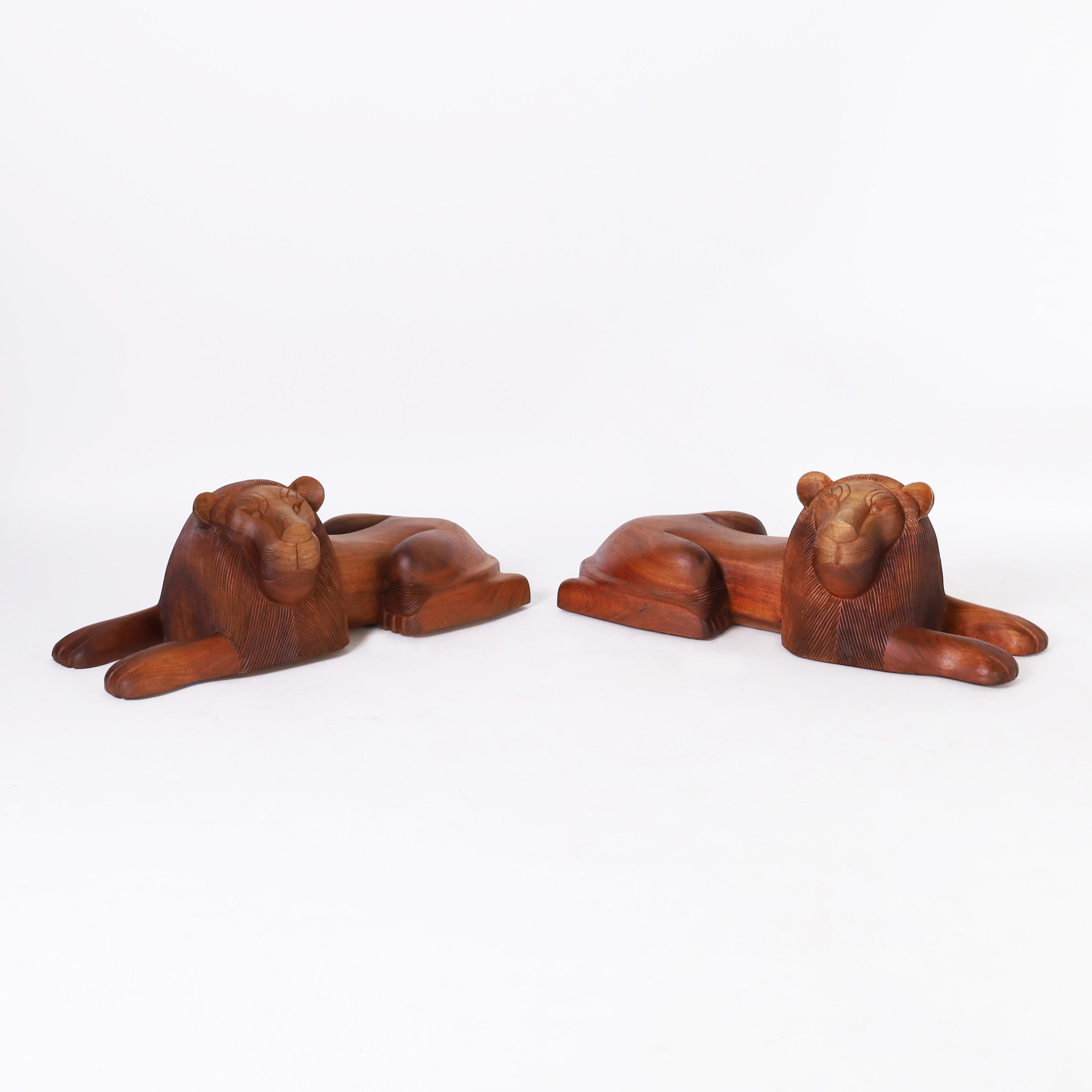 Rare and remarkable pair of mid century lions in repose hand carved, in a stylized modern form, from the Cammatillo tree or Kingwood grown in the Minas Gerais region of Brazil.