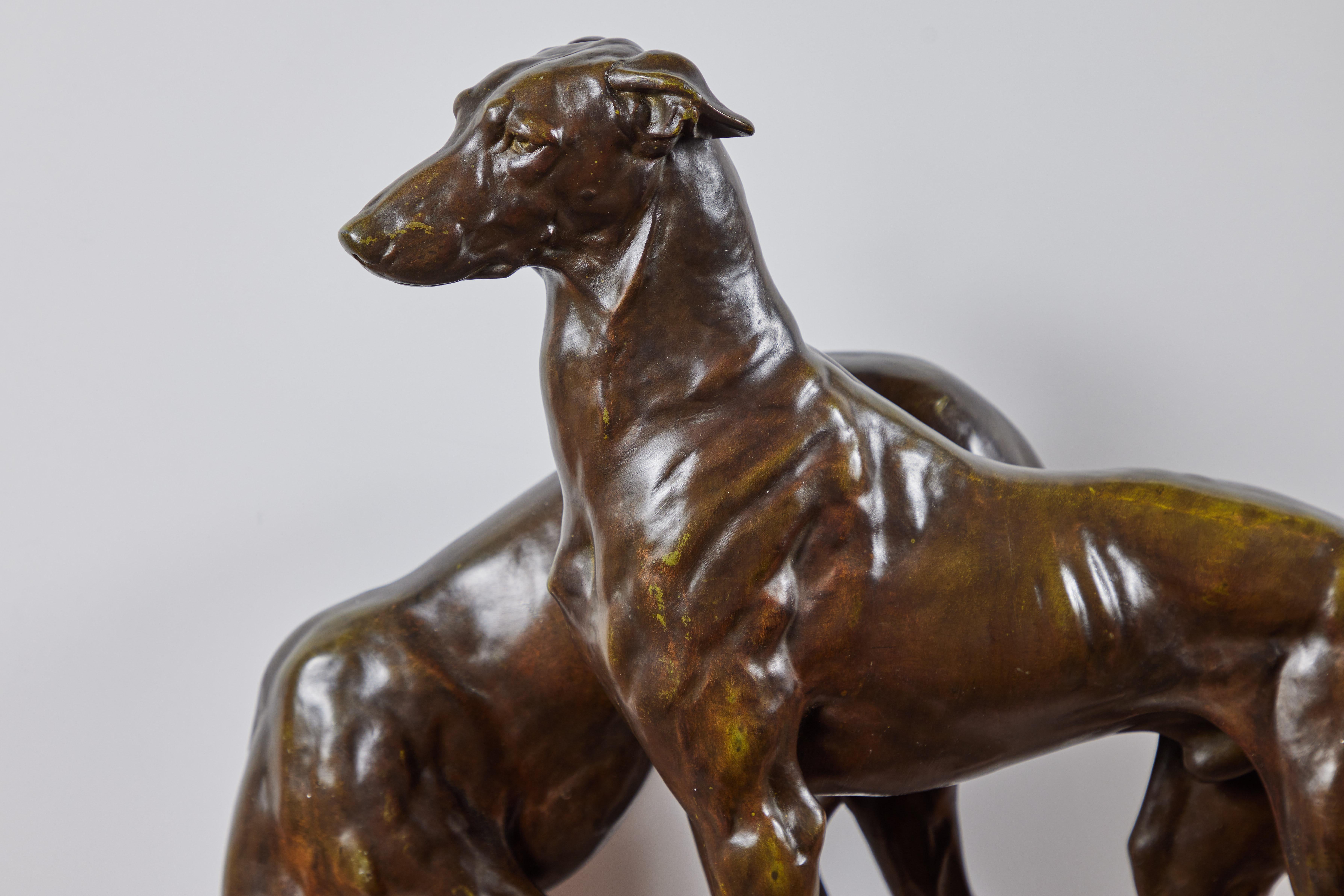 Un'elegante coppia di segugi in bronzo patinato degli anni '20, inizialmente concepiti e creati dal maestro scultore J.E. Masson (1871-1932). Questa edizione è stata fusa presso la rinomata fonderia d'arte Le Verrier di Parigi. Montata su una base