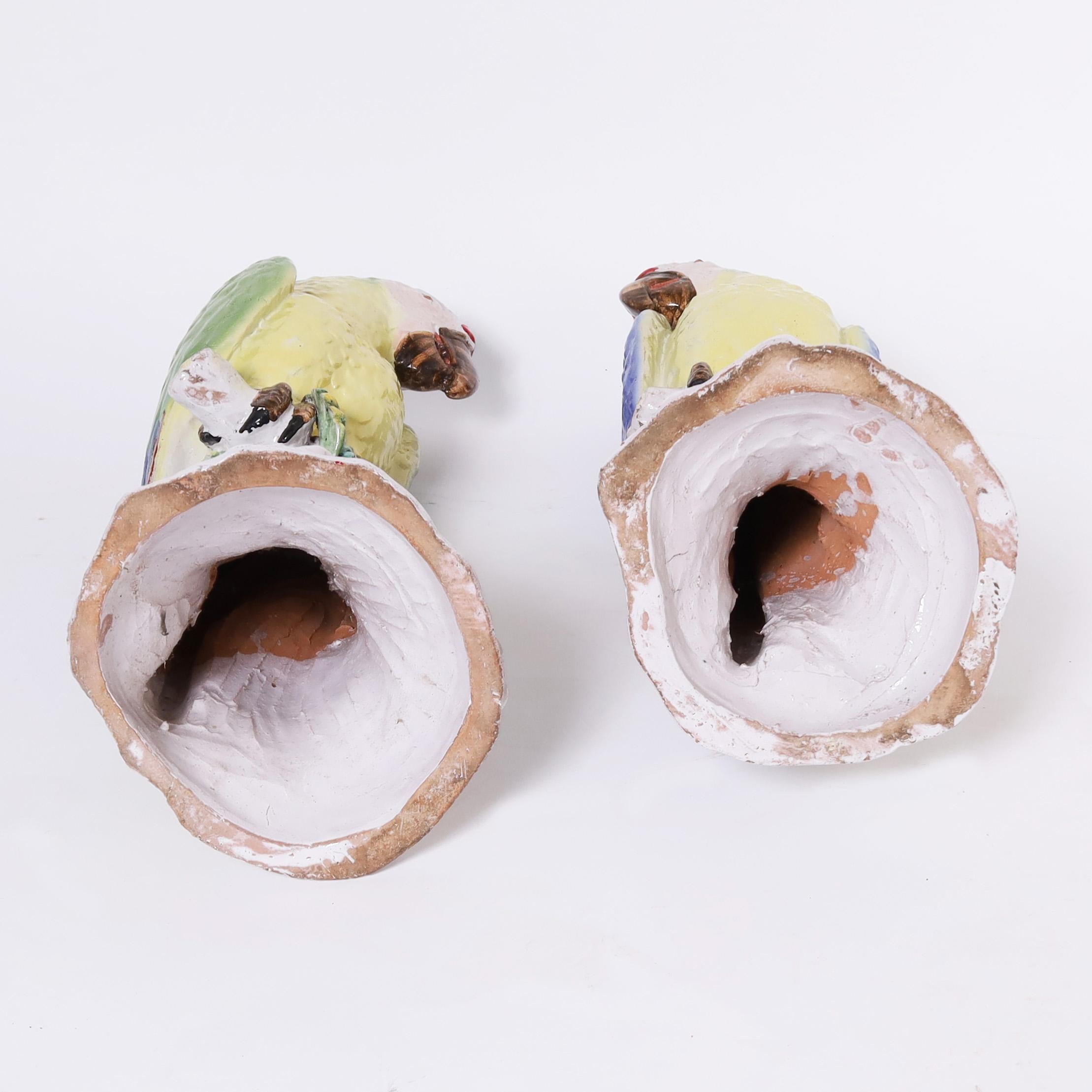 Auffallendes Paar Papageien-Skulpturen oder Figuren, die auf Sockeln mit Blättern und Beeren thronen. Sie sind aus Terrakotta in großem Maßstab gefertigt, von Hand dekoriert und glasiert. 