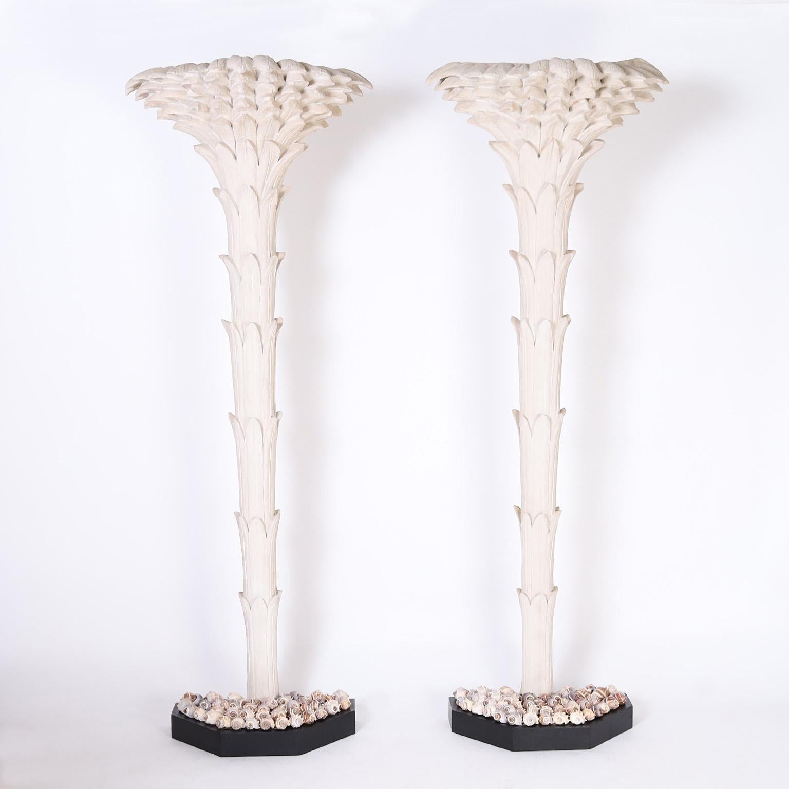 In vogue pair of mid-century stylized palm tree sculptures crafted in cast fiberglass. Painted in an off white finish and presented in faux planters filled with seashells.