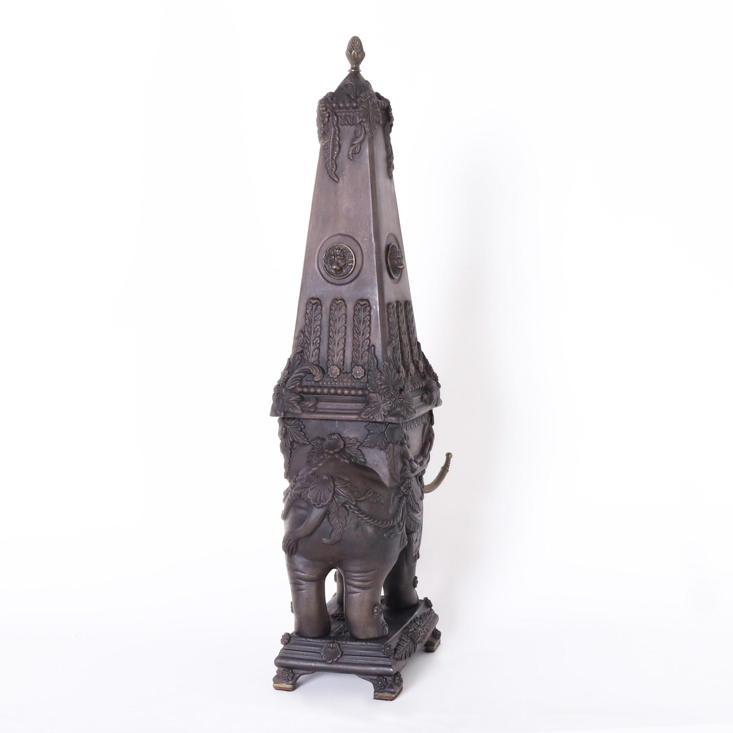 Vintage pair of Italian neoclassic garnitures or objects of art depicting elephants carrying obelisks, crafted in ceramic or earthenware with a bisque finish and highlighted with bronze finials, lion heads and tusks.