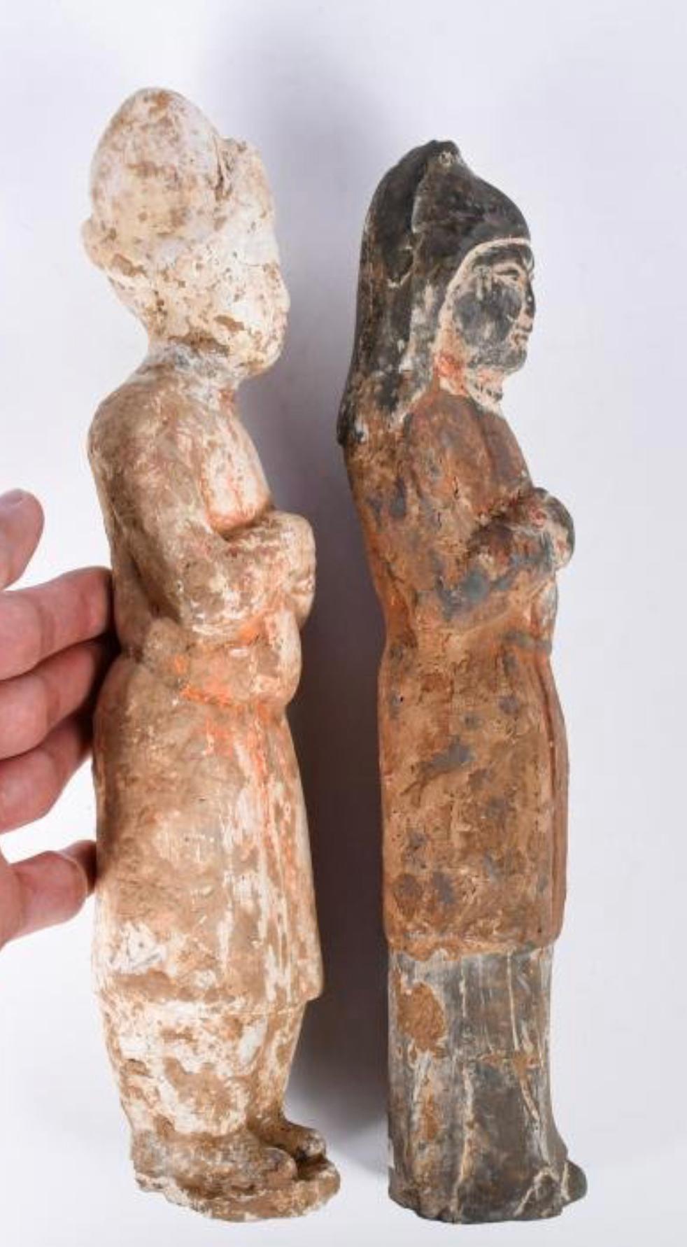 Dieses Set aus zwei bemalten Steingutfiguren ist ein Paar aus der Tang-Dynastie. Beide Figuren in langen roten Mänteln in stehender Position, die Frau mit gefalteten Händen, der bärtige Mann mit einer Hand auf der Brust, H:25cm & 25.6cm