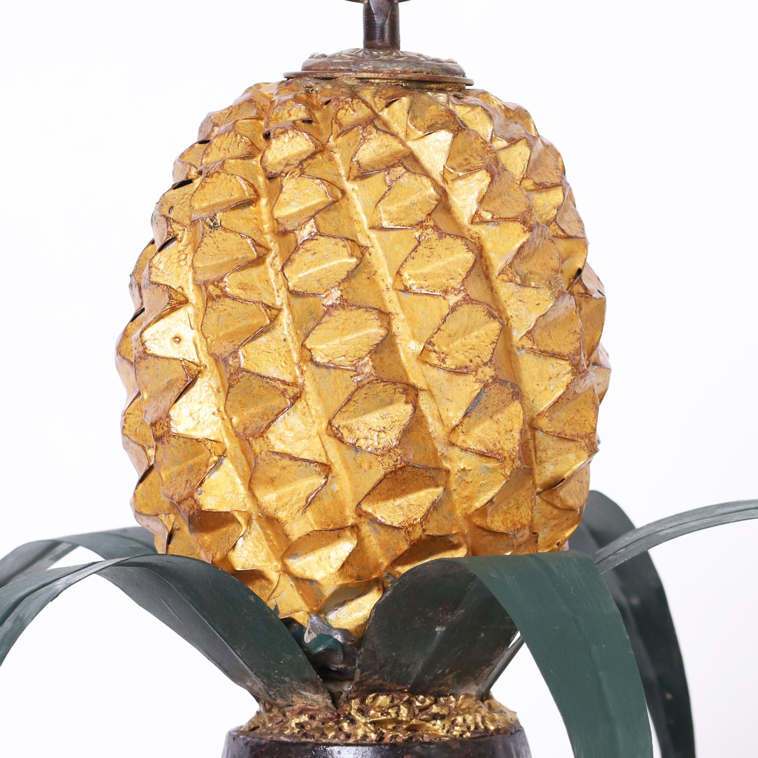 Standout pair of midcentury Italian tole pineapple garnitures or objects of art featuring stylized finials over pineapples with leaves on classical bases with a touch of whimsy.