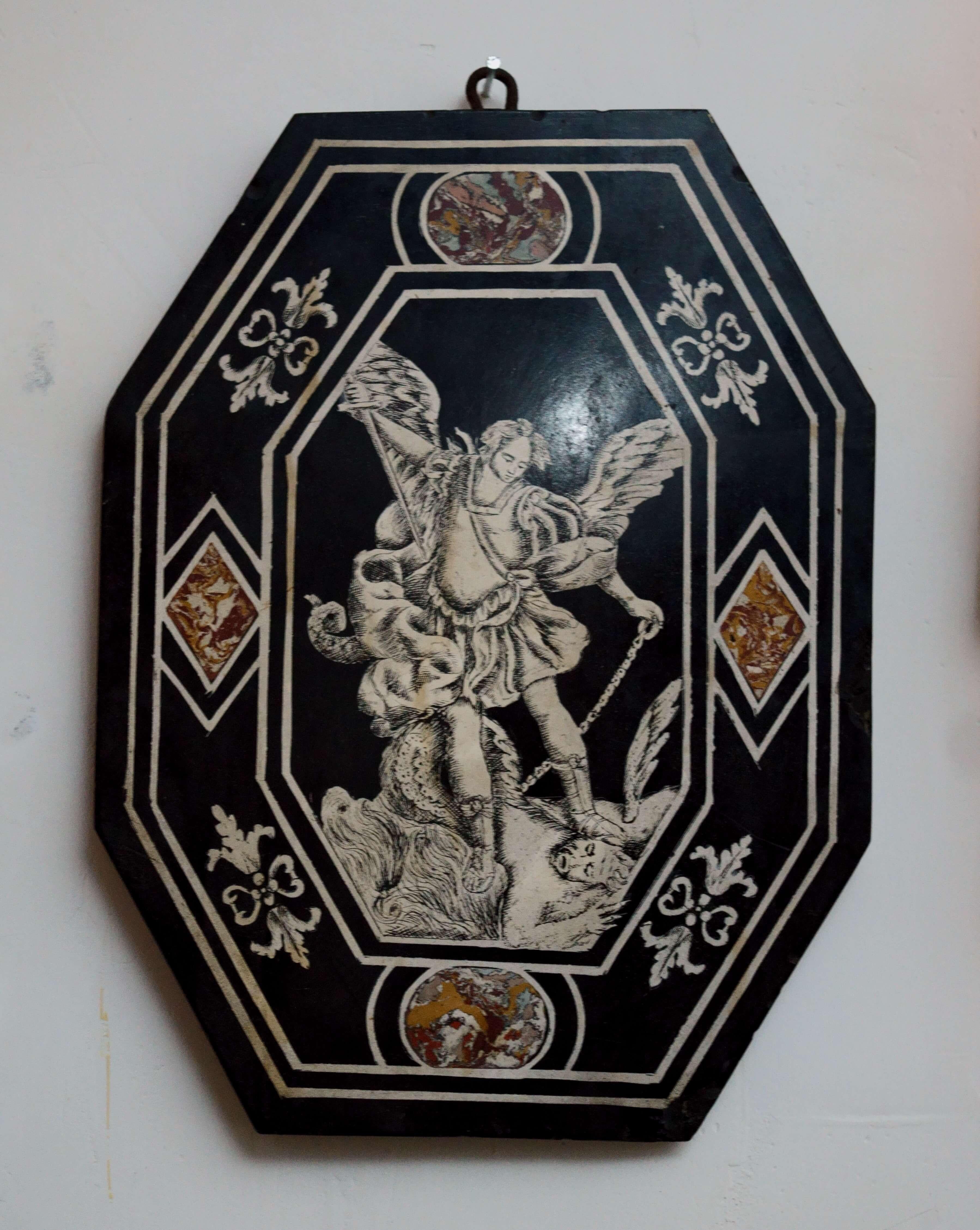 Carpi, metà del XVII secolo, pannello in scagliola.

La tavola, in bicromia bianca e nera, presenta inserimenti di elementi policromi marmorizzati e una scena centrale raffigurante San Michele che sconfigge il diavolo.
Il motivo decorativo si ispira