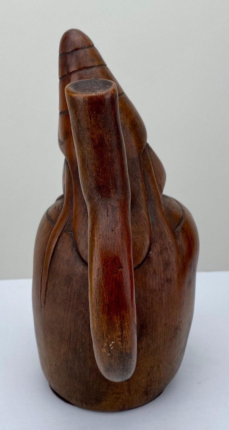 
Sculpture péruvienne figurative en bois sculpté d'après le vase à étrier Moche, Rêveur :  A  Le récipient à étrier prend la forme d'un homme assis, aux yeux fermés, aux traits animés, drapé dans un poncho, coiffé d'un casque conique et portant des
