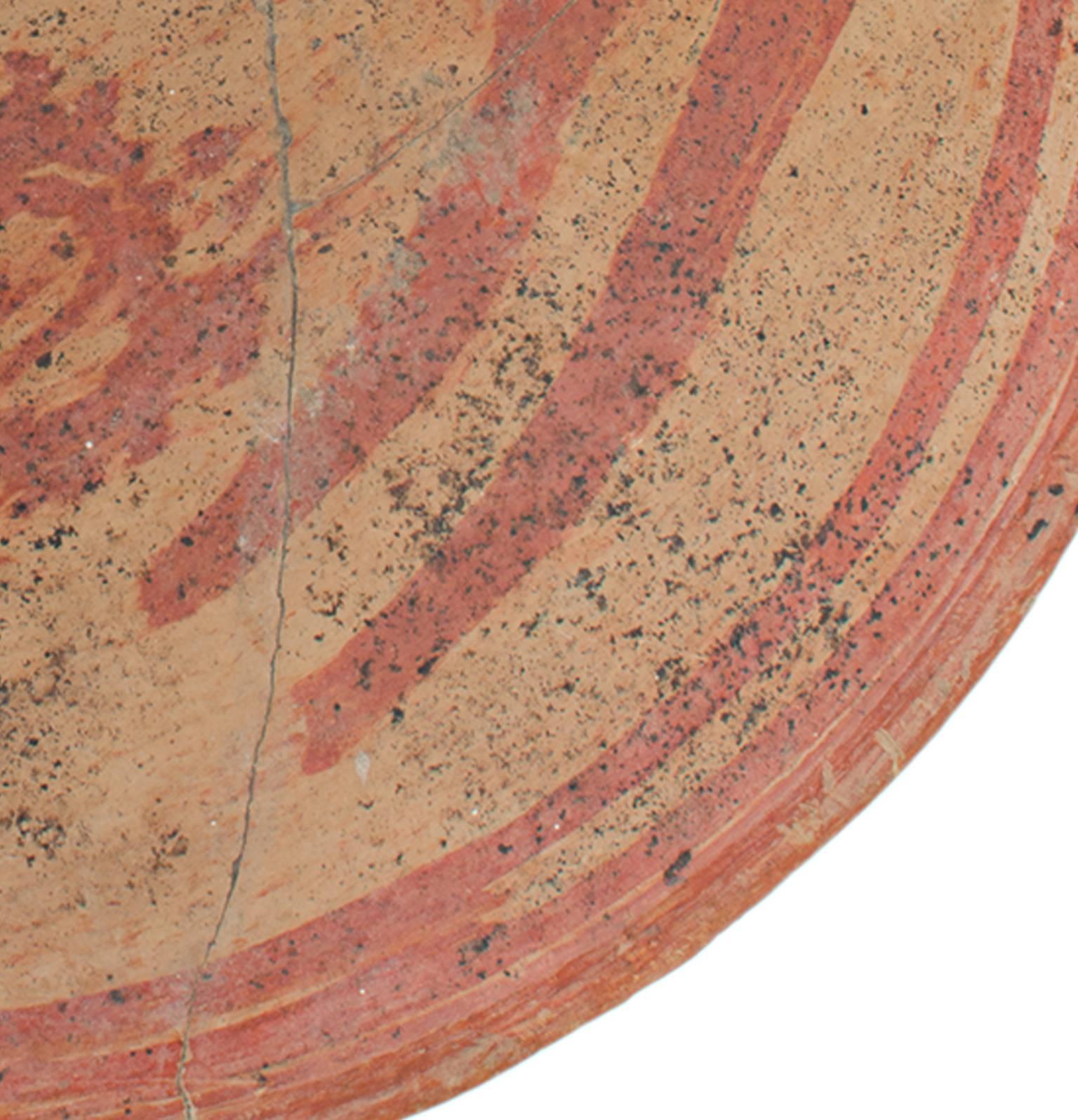 This Pre-Columbian bowl featuers red marks on a light orange ground. It is 9
