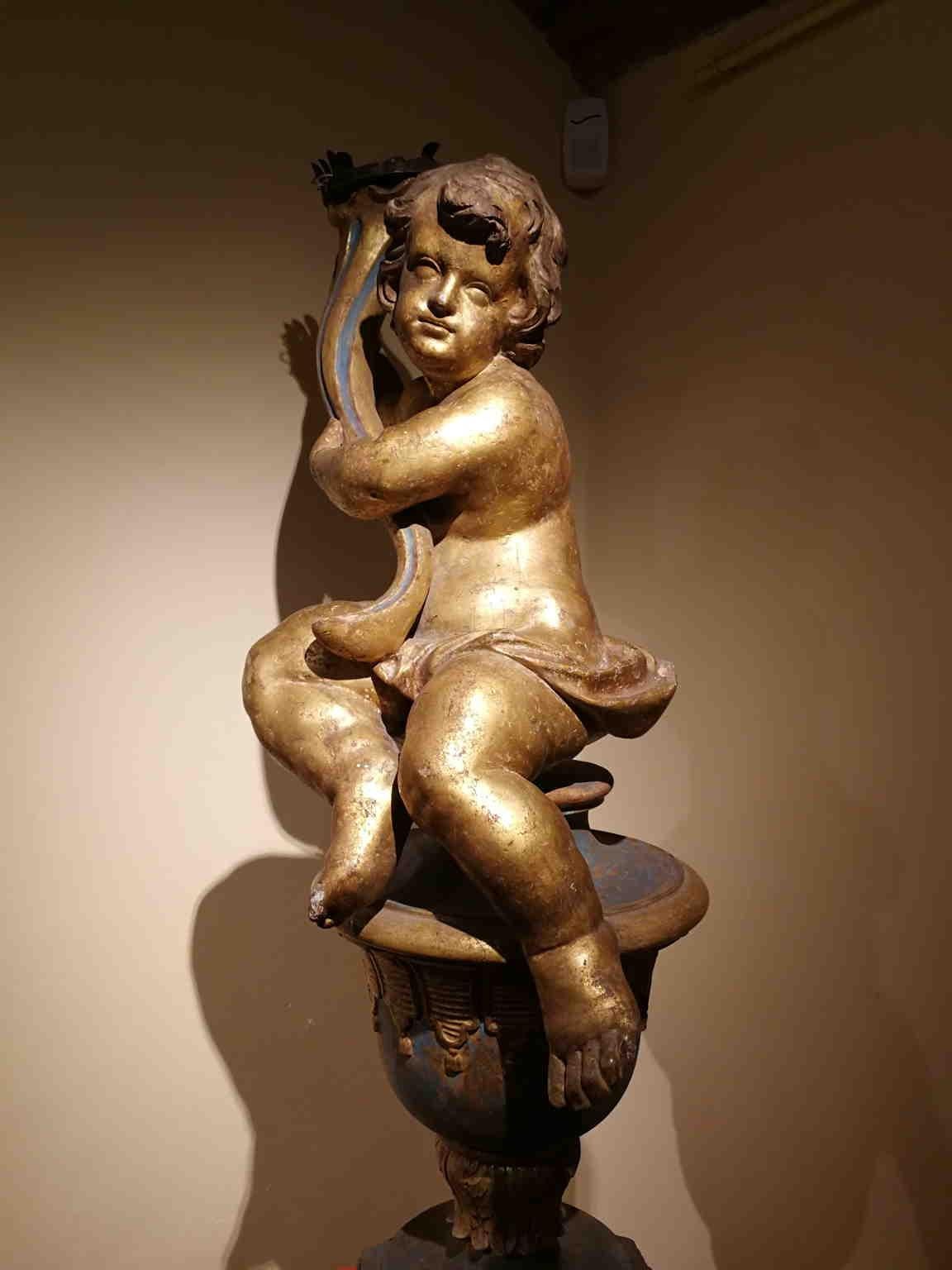Putto portavelas de una llama de madera dorada.
Este tipo de objetos estaban presentes en iglesias o villas nobles, sobre todo en la época barroca. 

La base no es coetánea.

