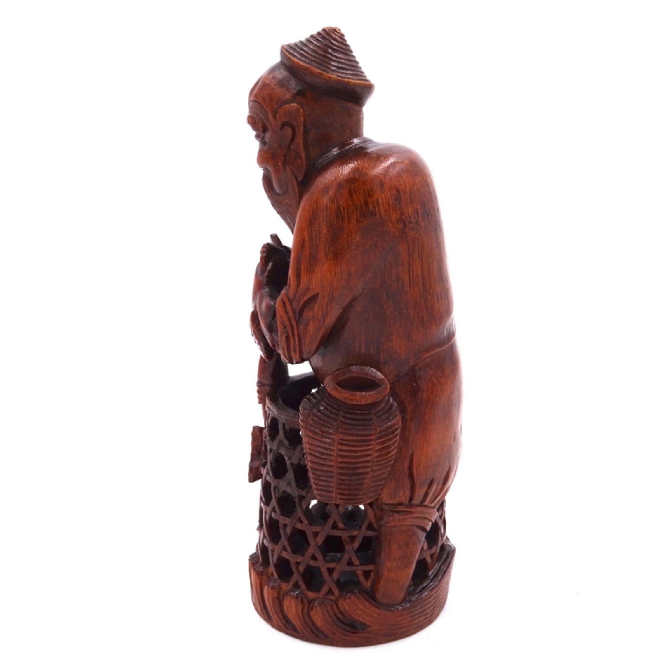Sculpture en bois de bambou représentant un pêcheur aux traits orientaux, avec une longue barbe et une coiffe, tenant deux poissons.

La partie inférieure est ornée d'un filet de pêche sculpté. 
L'œuvre est de provenance chinoise et peut être datée