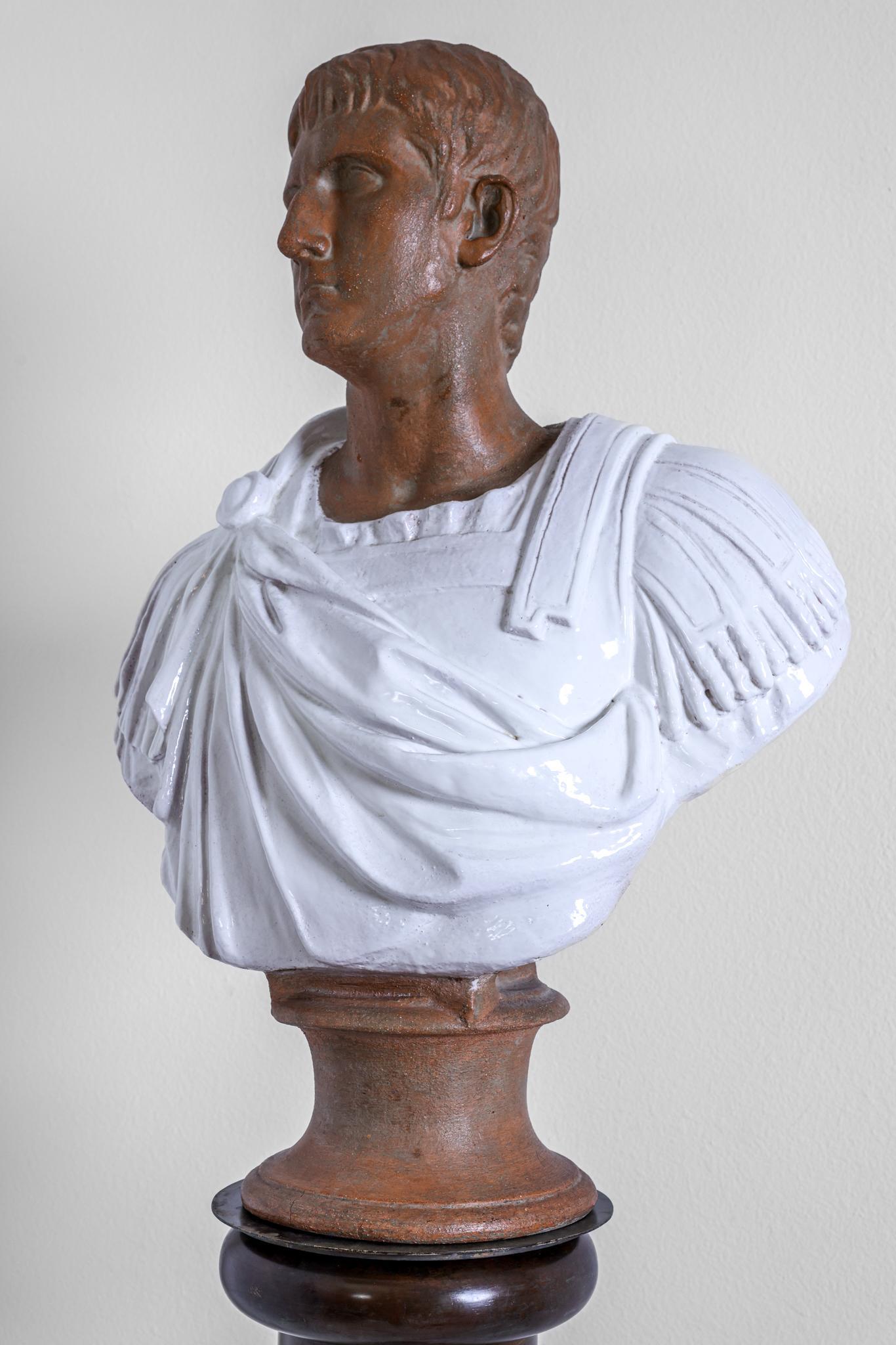 This terracotta sculpture depicts the bust of a Roman Senator or Emperor in armor and a gown. Hi gaze is directed at about a 45 degree angle. This is a magnificently robust life size bust. The garment has been fired in a white glaze. The bust has a