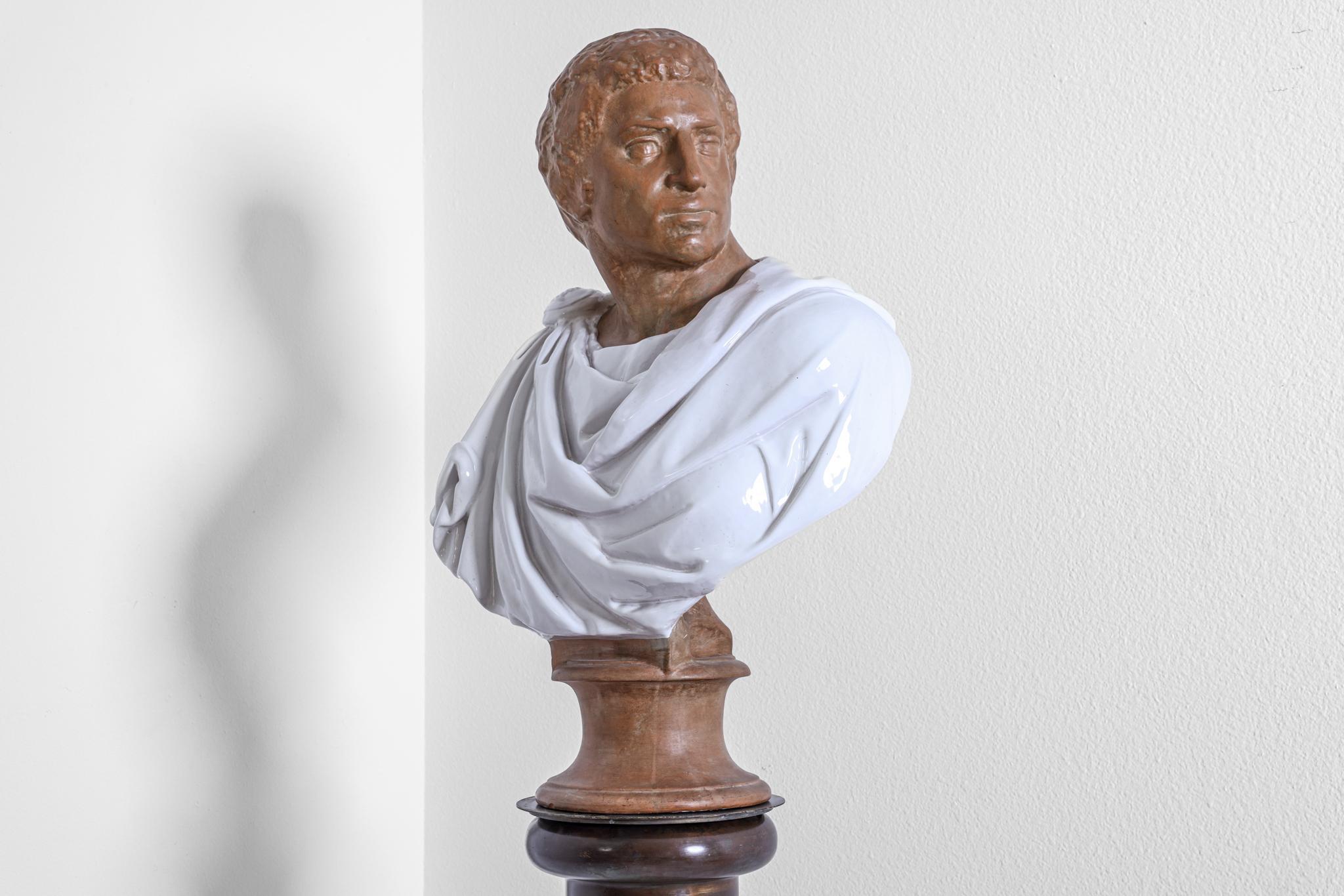 This terra-cotta sculpture no doubt depicts the bust of Roman Emperor or Senator in classical dress gazing over his left shoulder. This is a magnificently robust life size bust. His robe has been fired in a white glaze. The bust has a 7