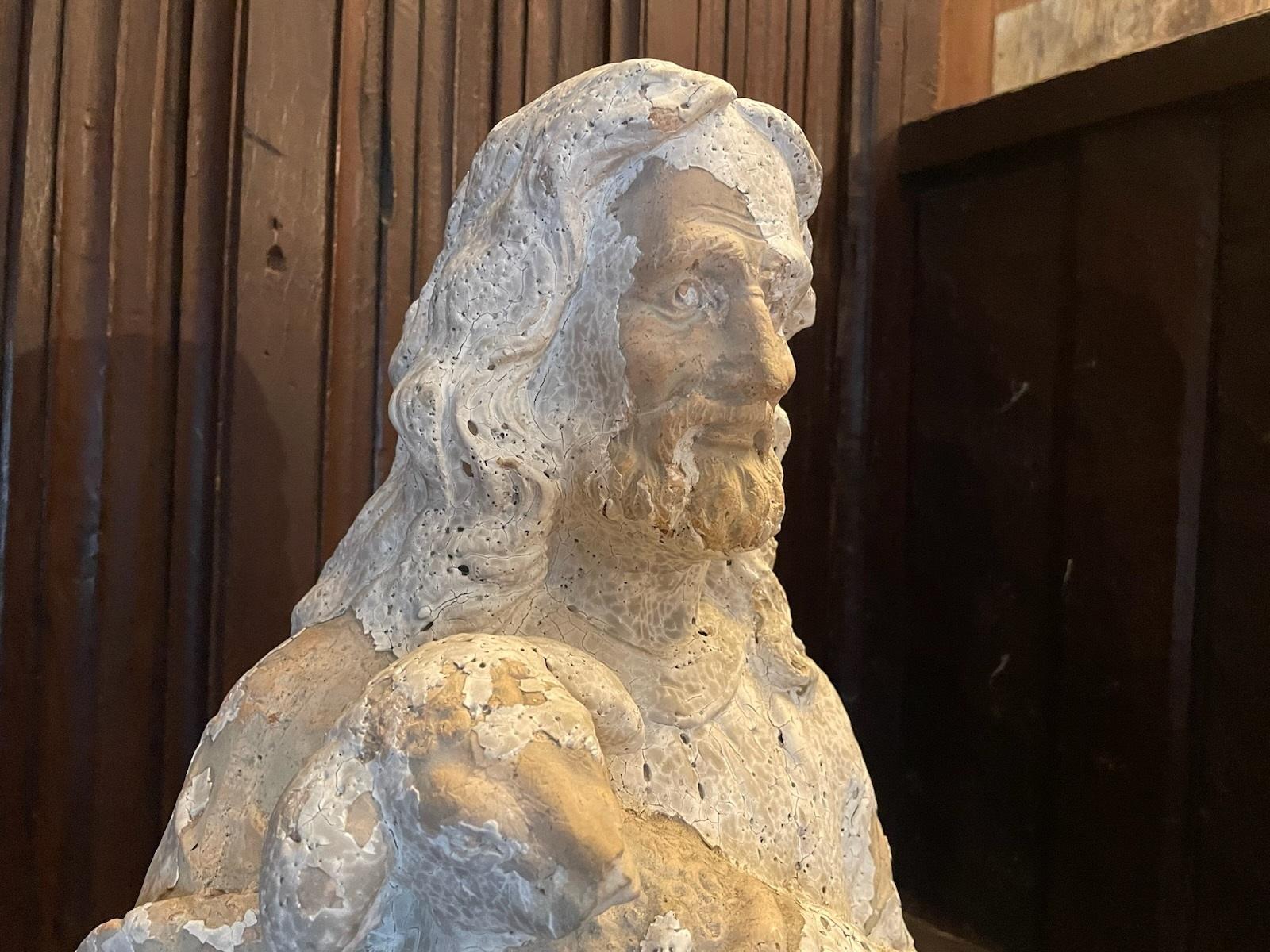 Religious sculpture of a bearded Christ holding a lamb. This beautiful sculpture is made from terracotta with a layer of gesso. The sculpture is in distressed condition with the layer of gesso flaked off in areas which gives the sculpture some