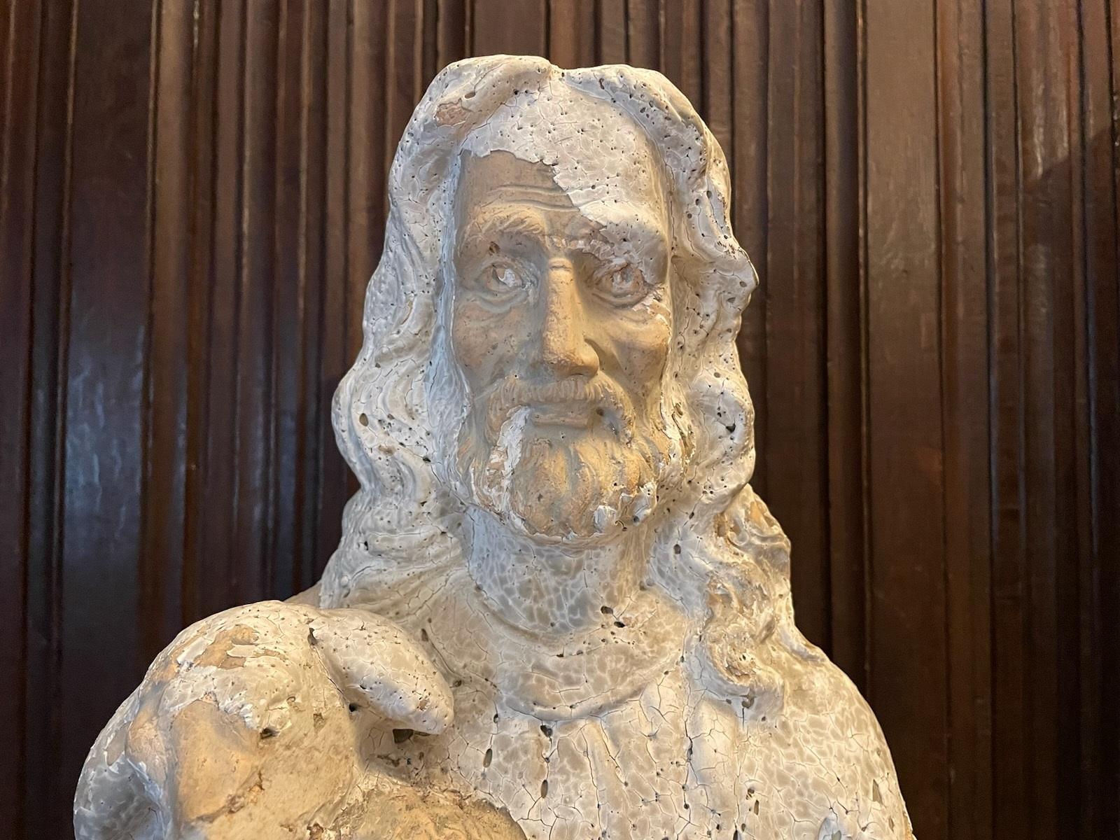 Sculpture religieuse représentant un Christ barbu tenant un agneau. Cette belle sculpture est réalisée en terre cuite avec une couche de gesso. La sculpture est en mauvais état, la couche de gesso s'étant écaillée par endroits, ce qui lui donne du