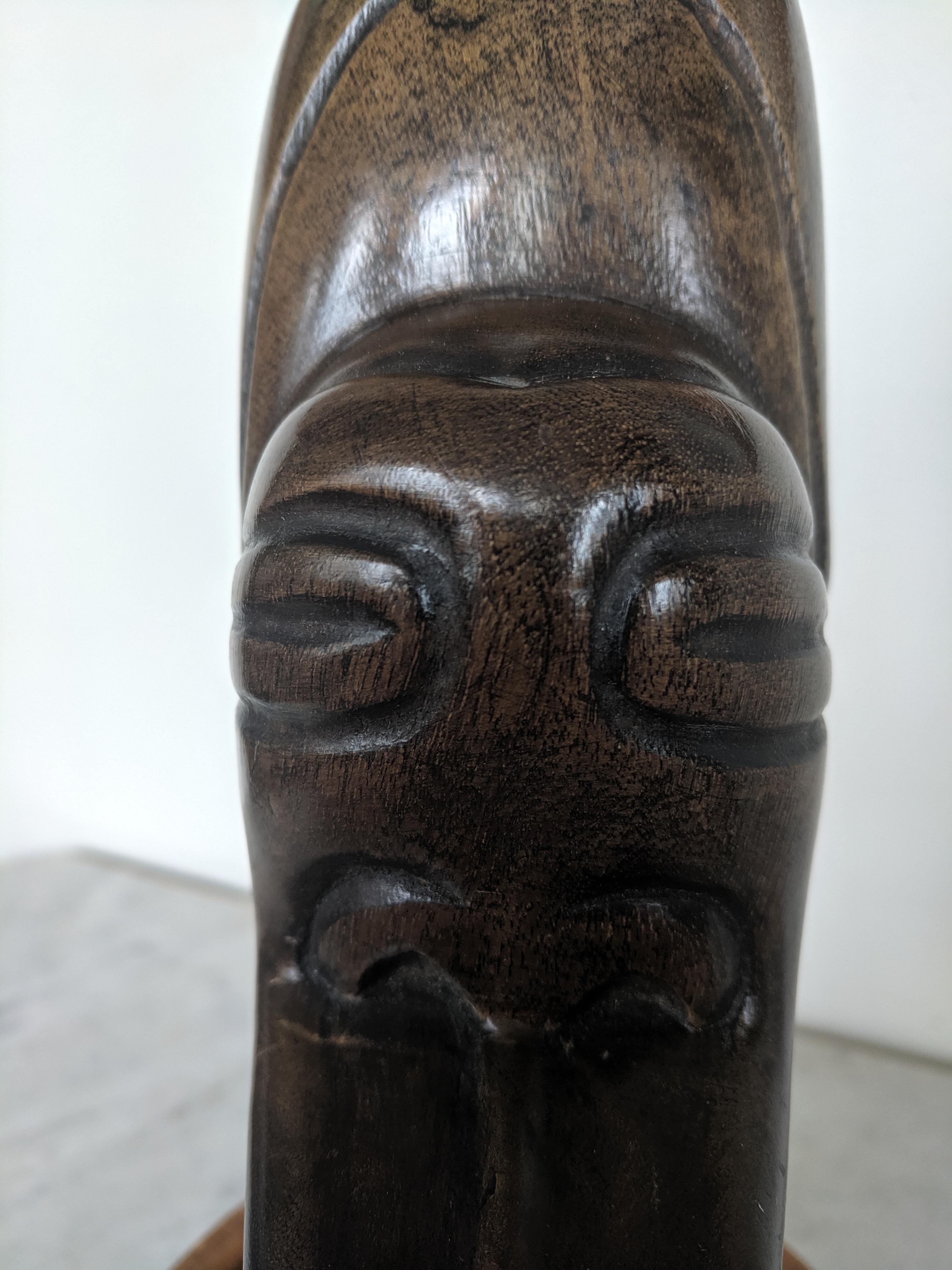 This sculptural head is made in Haiti from mahogany wood. The wood has a worn, dark brown patina. The carving is somewhat minimalistic, thus giving a modern twist to a tribal gesture. The head is signed underneath 