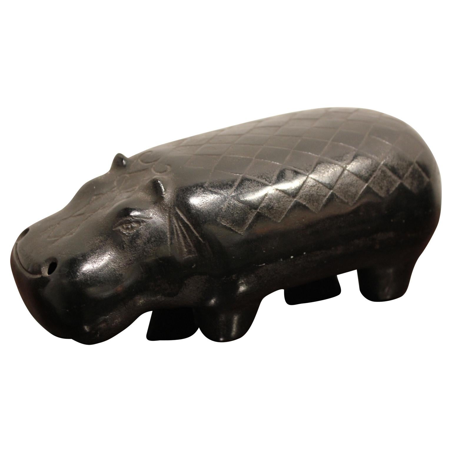 Hollow cast iron sculpture of a hippo with decorative checkered patterns along the back. 