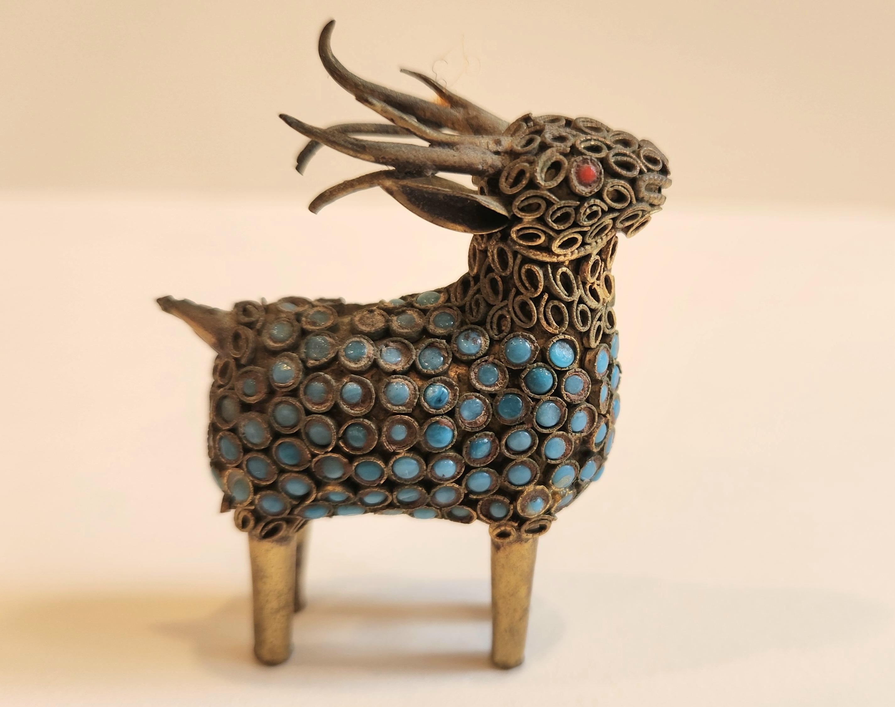 This delicate sculpture from Nepal is intricately with decorated turquoise stones around the body, and two coral stones representing the eyes. The head, neck, and portions of the body of this animal also have small pieces of coiled bronze